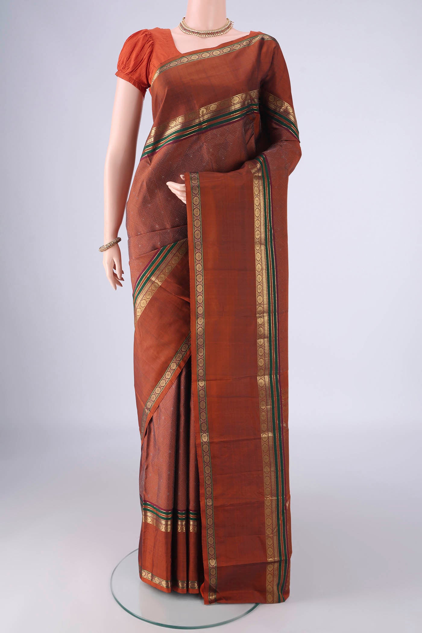 Rust Kanchipuram Silk Saree with Jacquard design on the body and Zari Border.  displayed on a mannequin