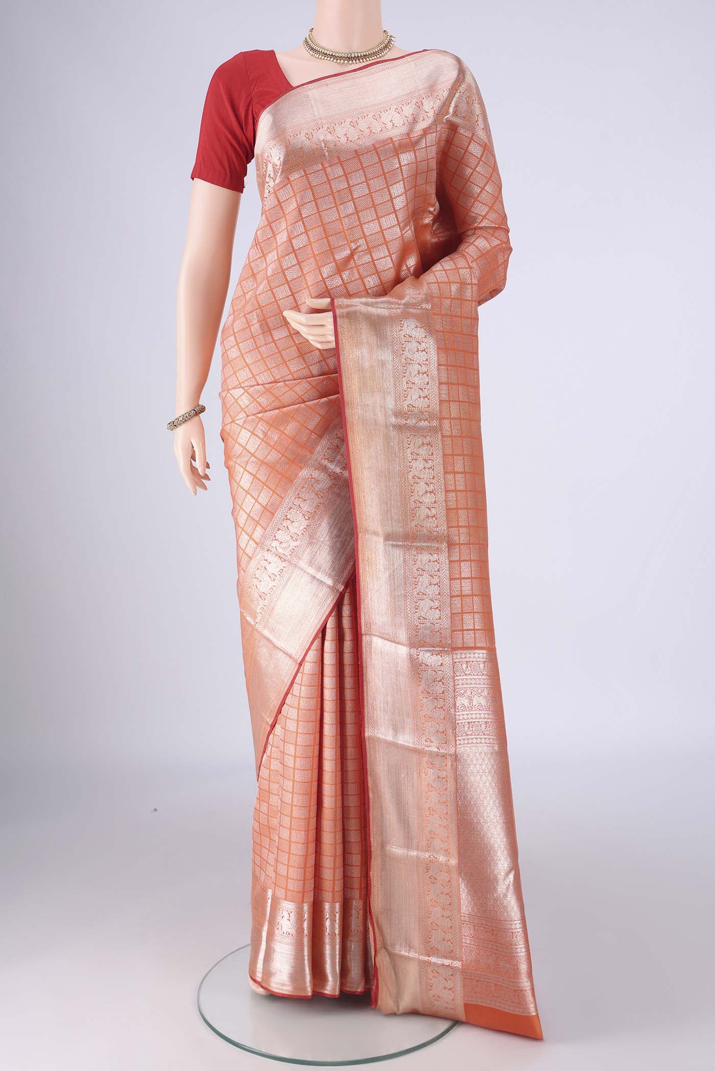 Orange Kanchipuram Silk Saree with Zari Brocade on the body and Zari Border.  displayed on a mannequin