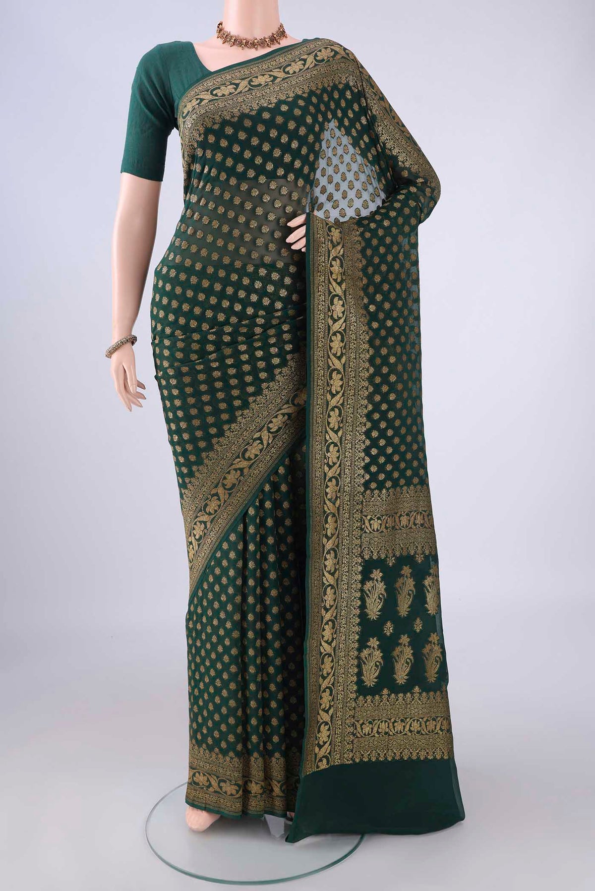 Bottle Green Banarasi Georgette Saree with Zari Butta on the body and Zari Border.  displayed on a mannequin