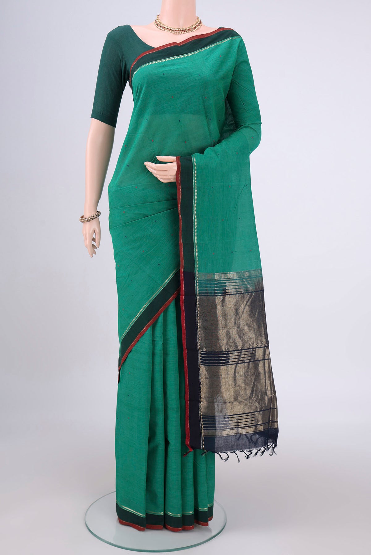 Bottle Green Kanchi Cotton Saree with Thread Butta on the body and Zari Border.  displayed on a mannequin