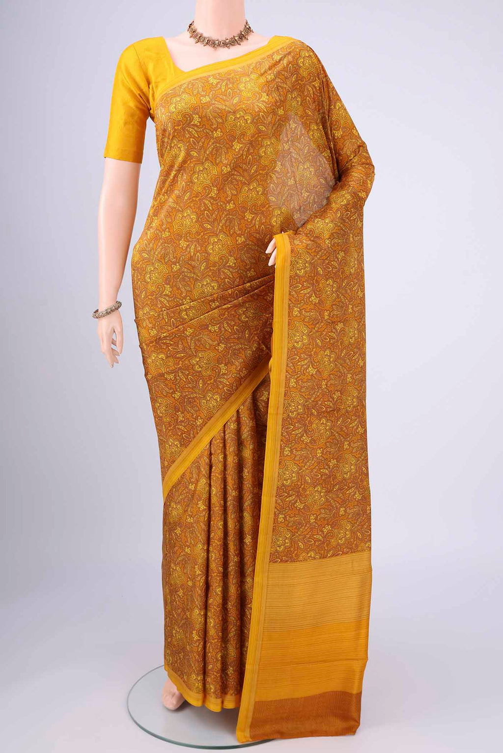 Mustard Printed Silk Saree with Floral Print on the body and Printed Border.  displayed on a mannequin