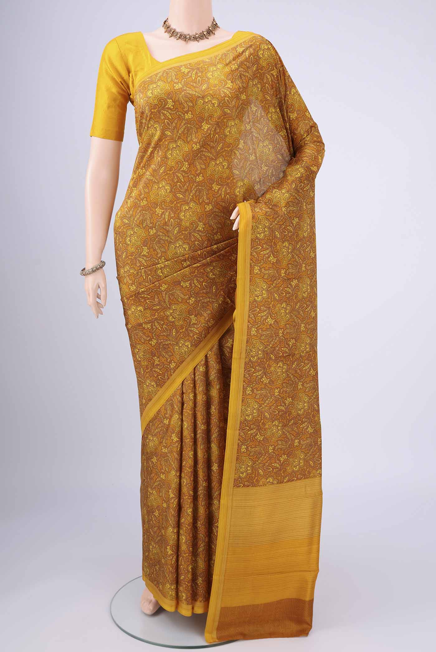 Mustard Printed Silk Saree with Floral Print on the body and Printed Border.  displayed on a mannequin