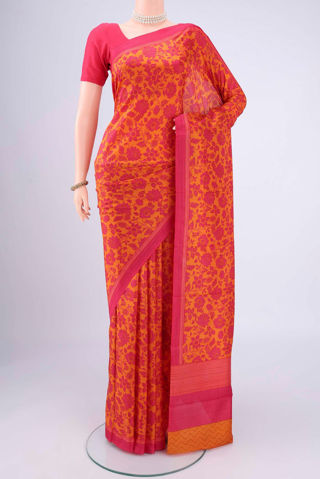 Mustard Printed Silk Saree with Floral Print on the body and Printed Border.  displayed on a mannequin