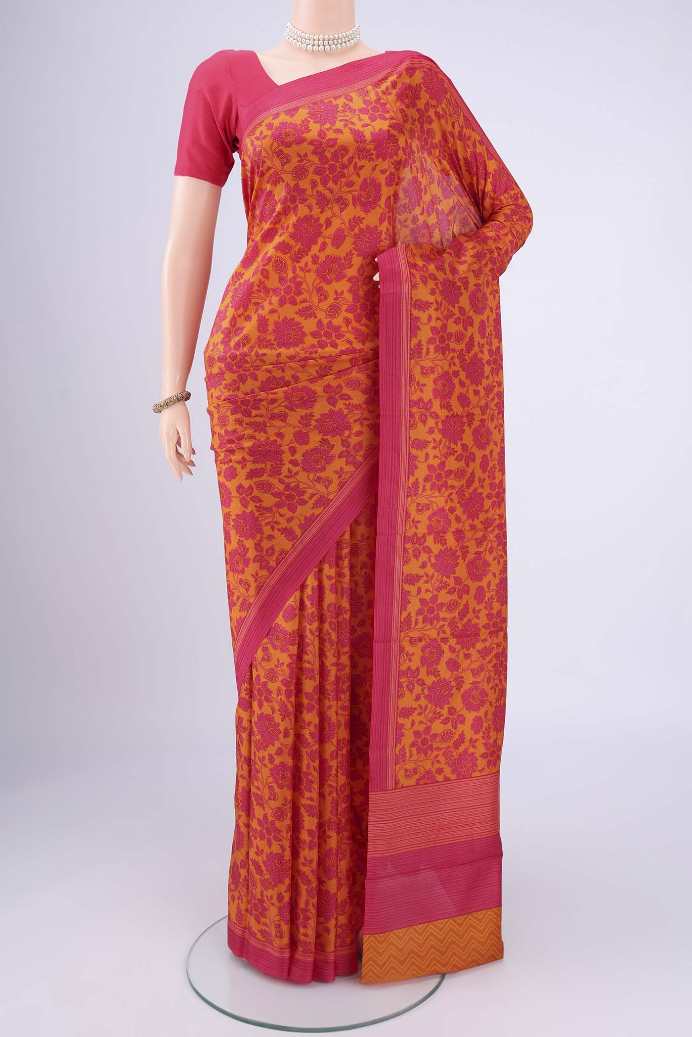 Mustard Printed Silk Saree with Floral Print on the body and Printed Border.  displayed on a mannequin