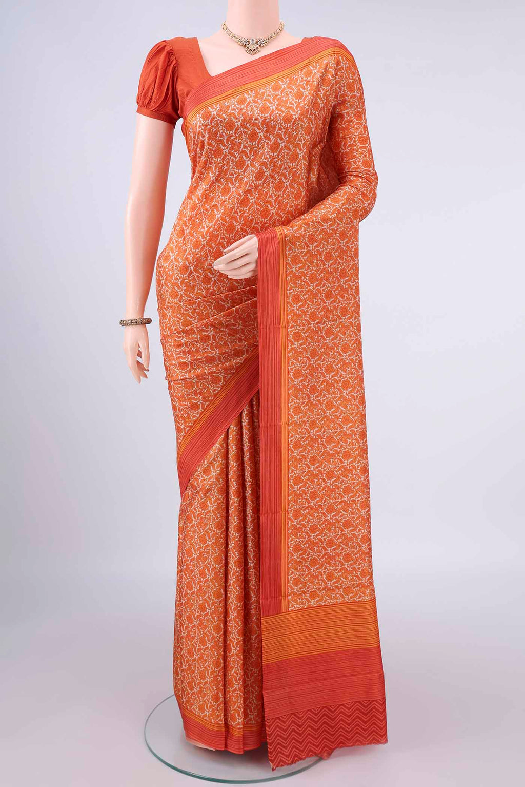 Pure Silk Orange Printed Saree with Printed design on the body and Plain Border.  displayed on a mannequin