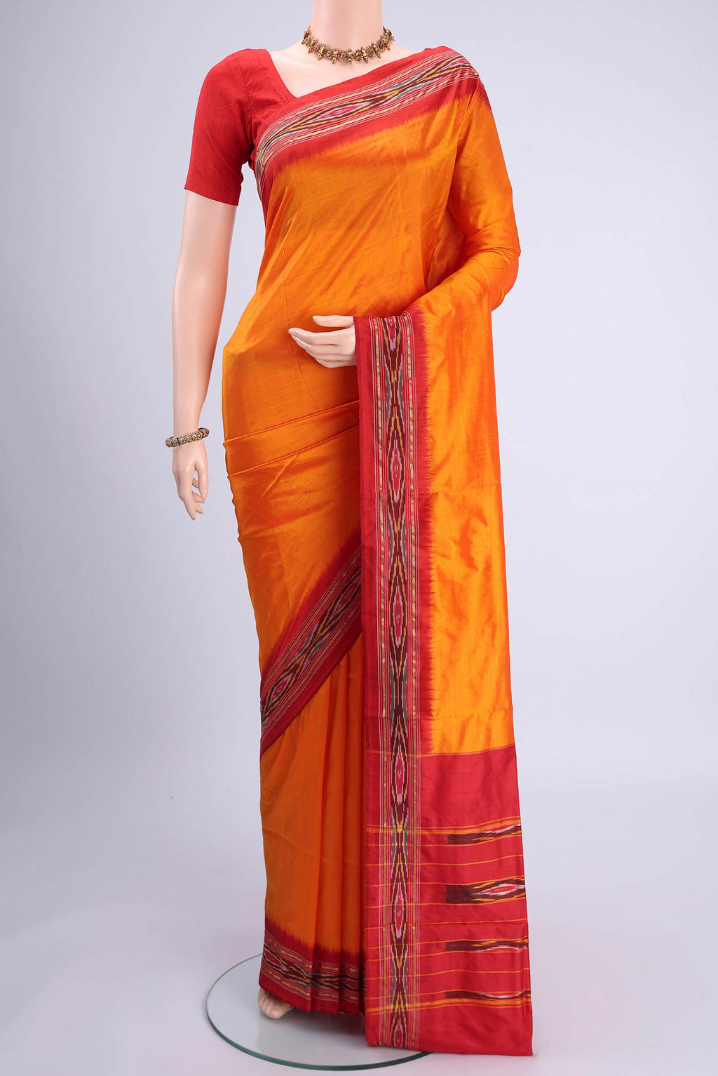 Orange Pochampally Silk Saree with Plain Body and Ikat Border.  displayed on a mannequin