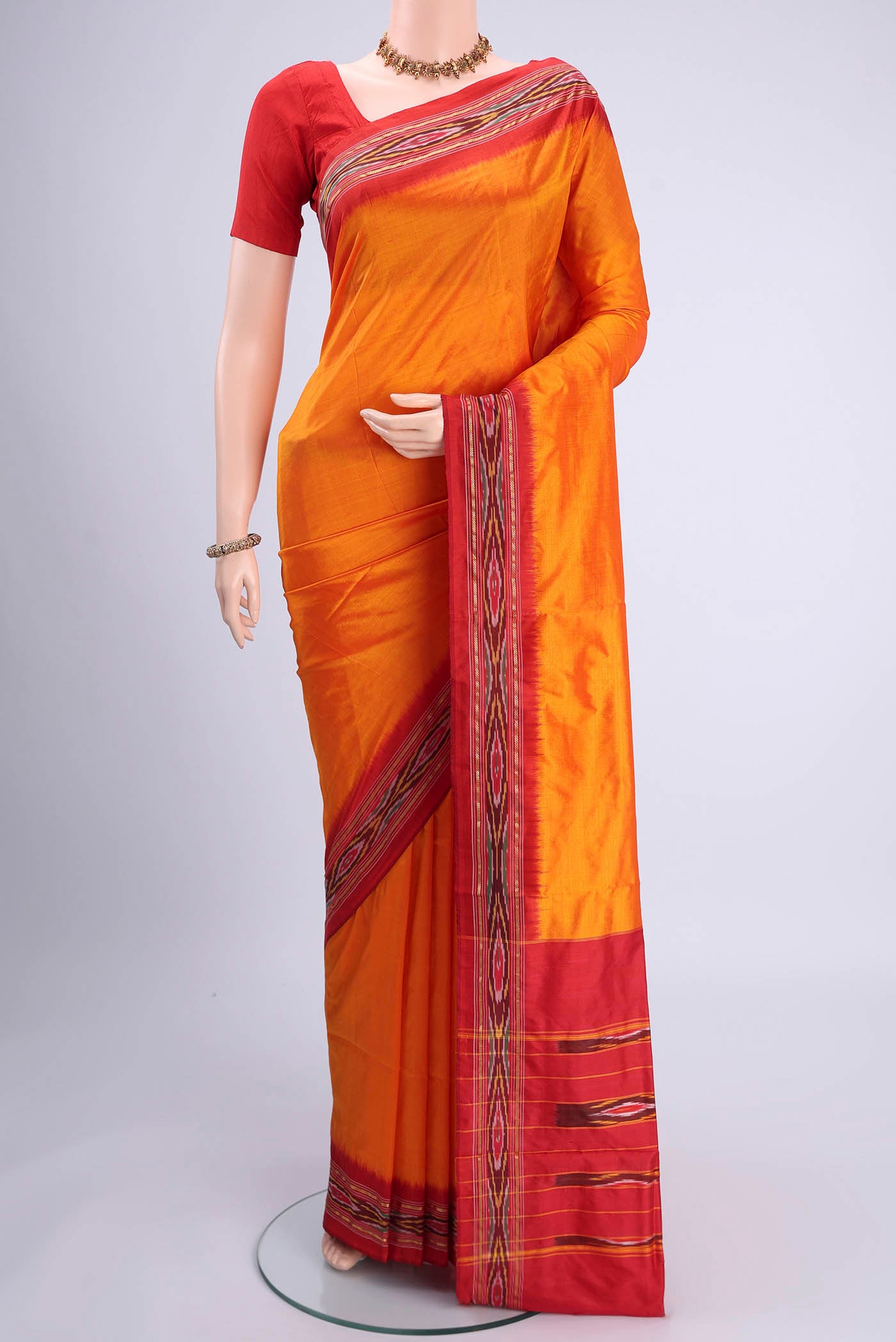 Orange Pochampally Silk Saree with Plain Body and Ikat Border.  displayed on a mannequin