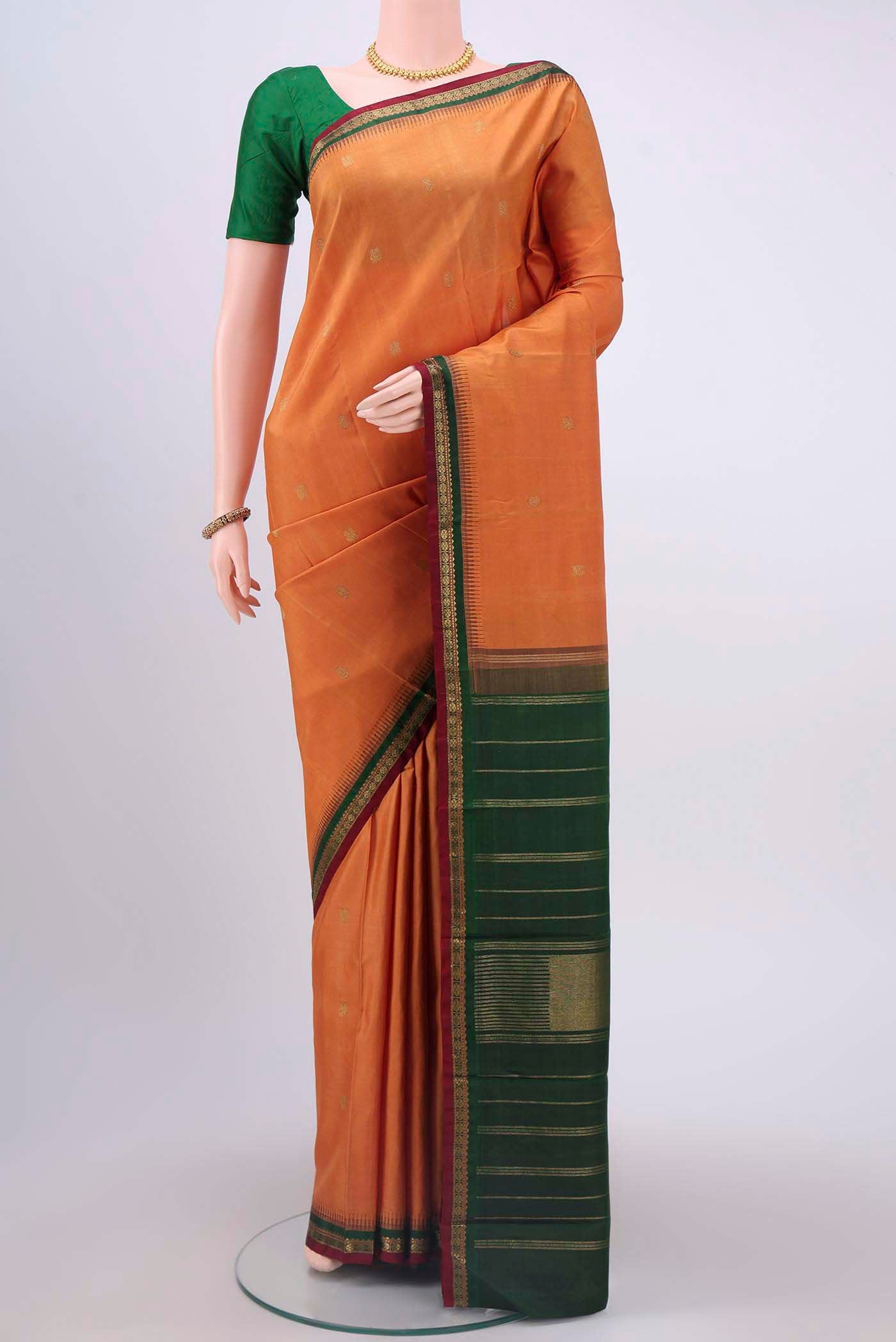 Brick Orange Kanchipuram Silk Saree with Zari Butta on the body and Zari Border displayed on a mannequin