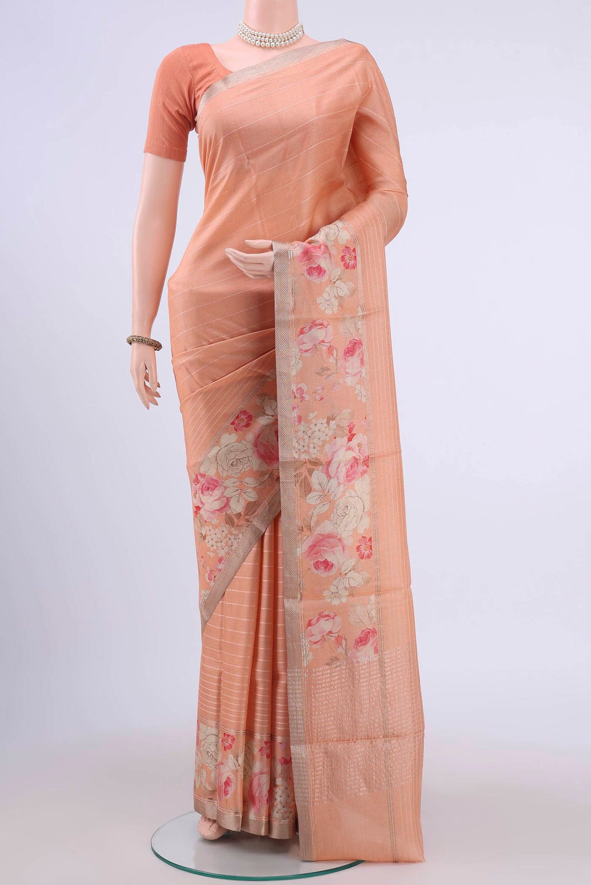 Peach Tussar Silk Saree with Floral Print on the body and Zari Border displayed on a mannequin