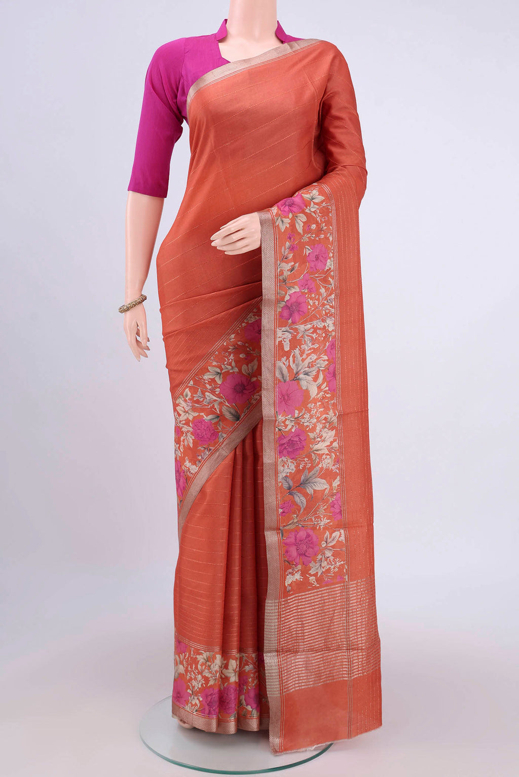 Rust Tussar Silk Saree with Printed design on the body and Zari Border.  displayed on a mannequin