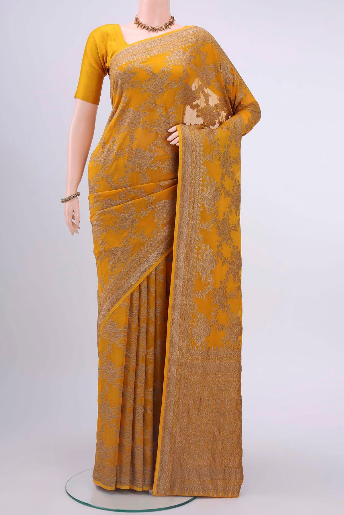 Mustard Banarasi Georgette Saree with Zari Butta on the body and Zari Border displayed on a mannequin