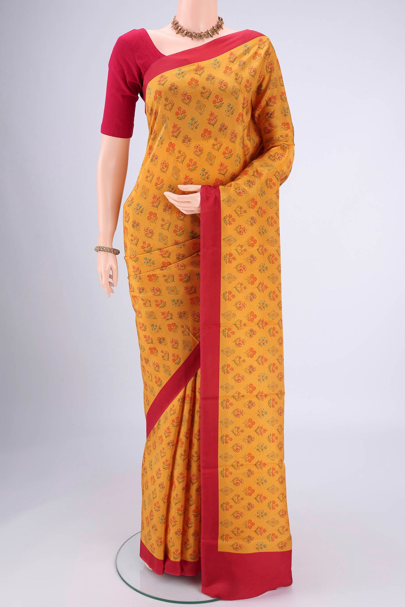 Mustard Printed Silk Saree with Floral Print on the body and Printed Border.  displayed on a mannequin