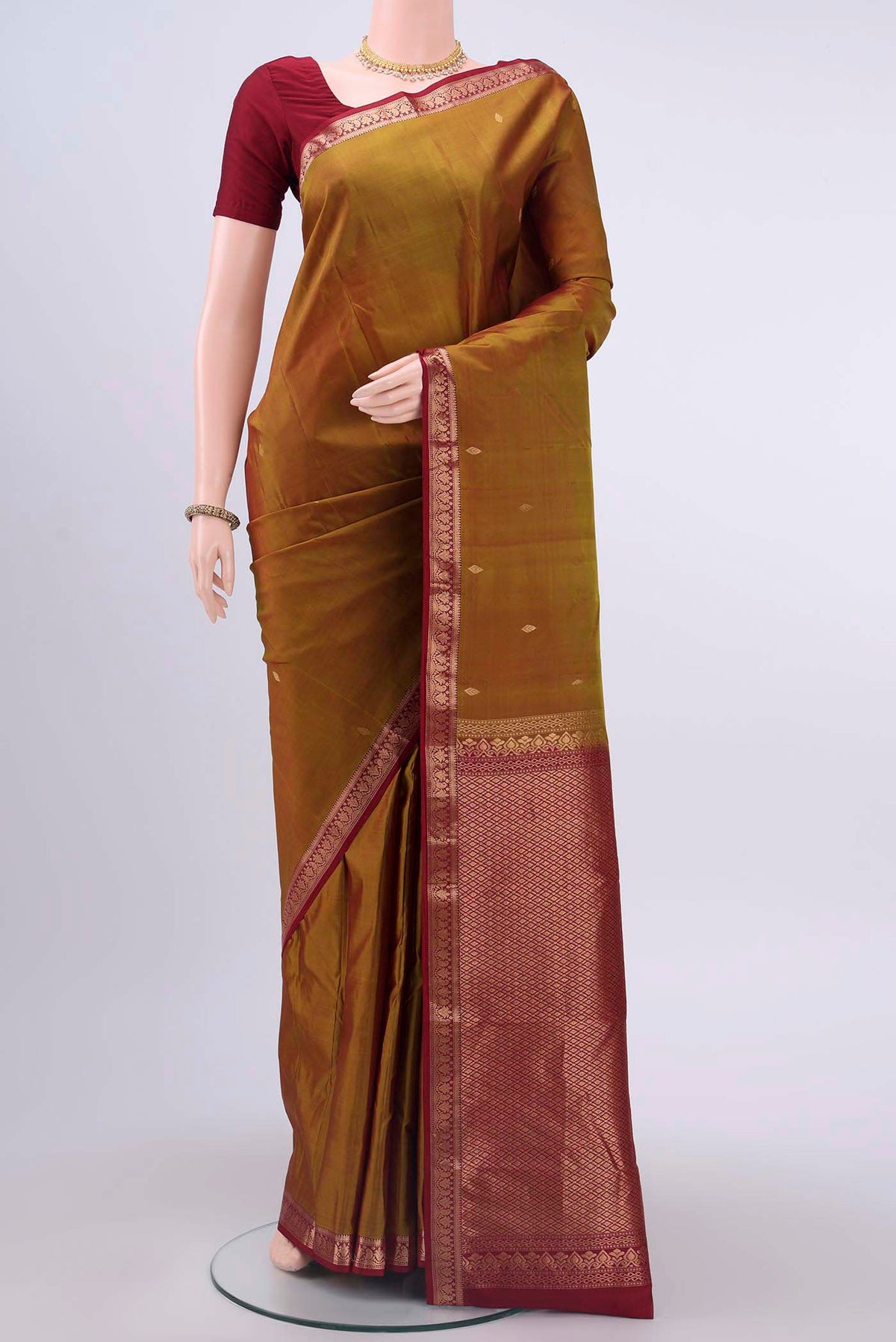 Mustard Kanchipuram Silk Saree with Zari Butta on the body and Zari Border displayed on a mannequin