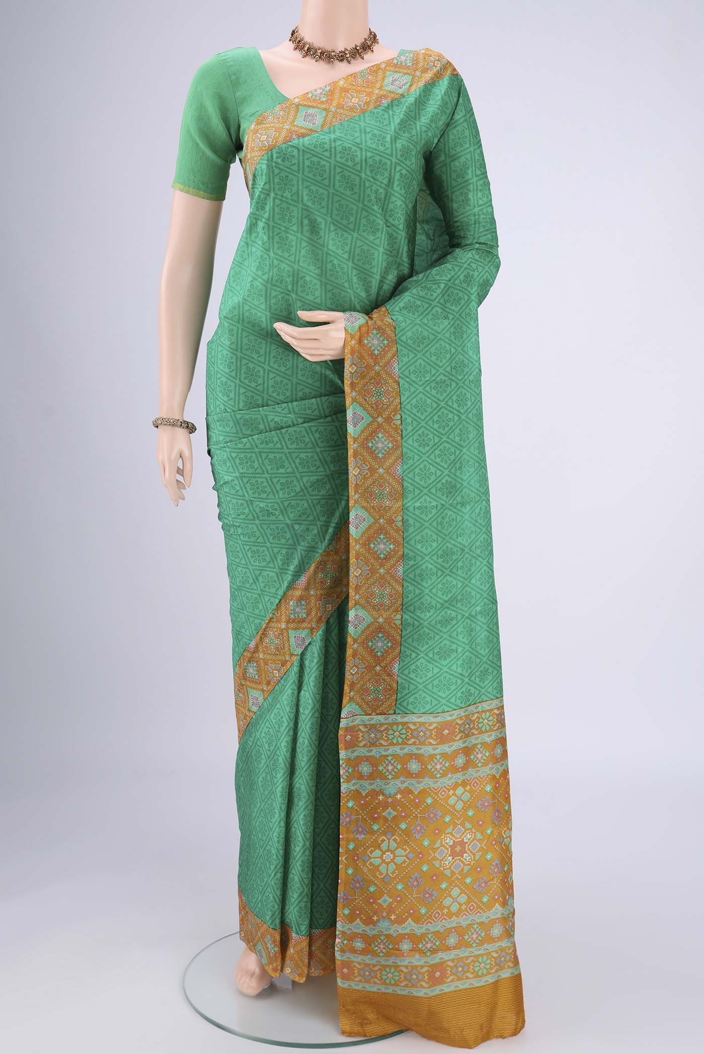 Green Printed Silk Saree with Floral Print on the body and Printed Border.  displayed on a mannequin