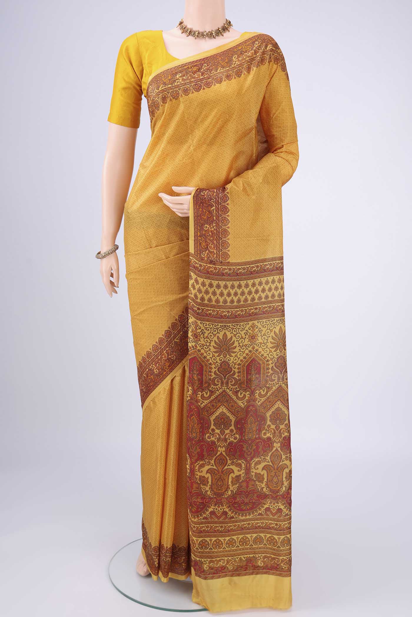 Mustard Printed Silk Saree with Floral Print on the body and Printed Border.  displayed on a mannequin