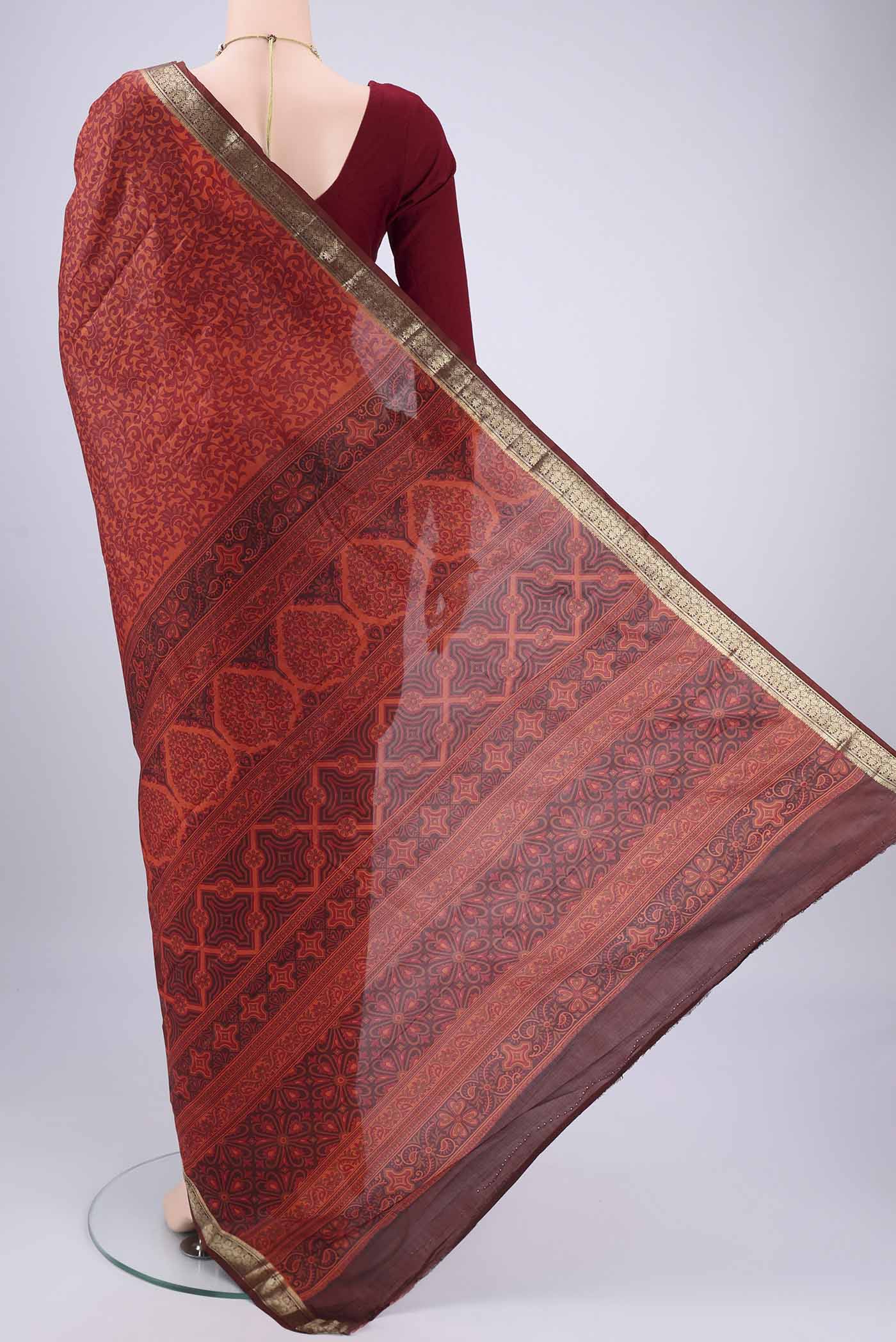 Flat view of Rust Printed Silk Saree with Printed design on the body and Zari Border. 