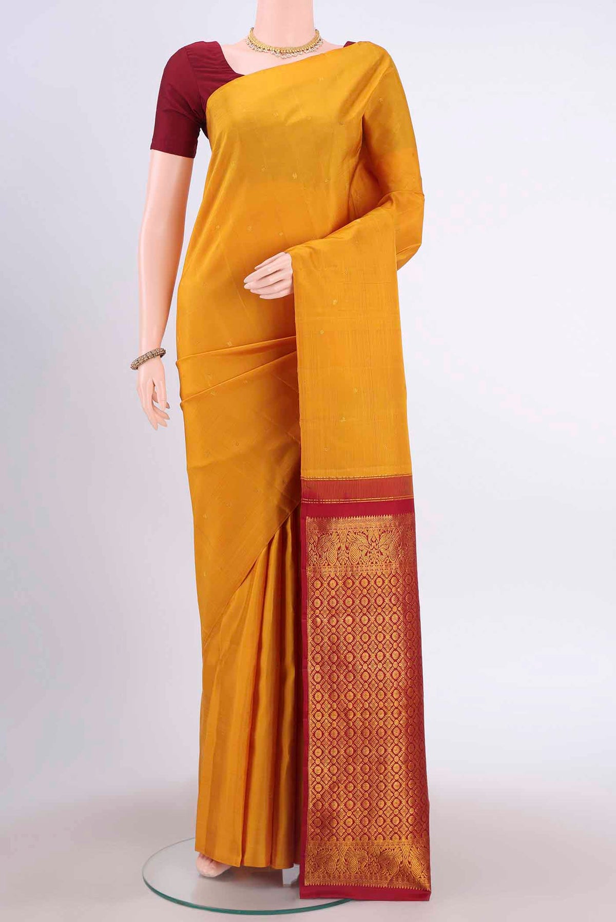 Mustard Kanchipuram Silk Saree with Zari Butta on the body and Without Border displayed on a mannequin