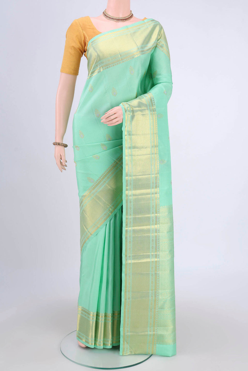 Mint Green Kanjivaram Saree with Zari And Thread Butta on the body and Zari Border.  displayed on a mannequin