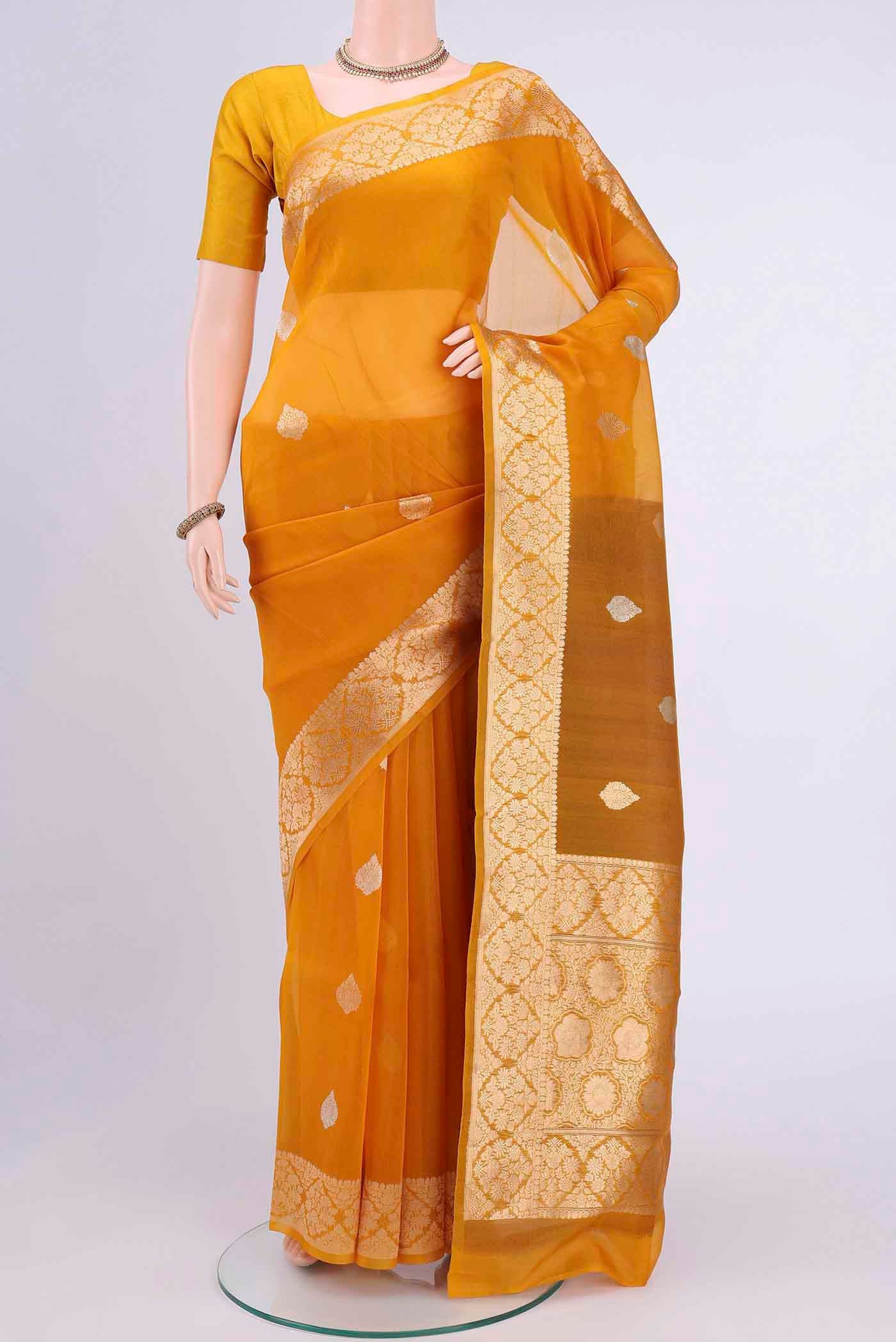 Mustard Organza Silk Saree with Zari Butta on the body and Zari Border displayed on a mannequin
