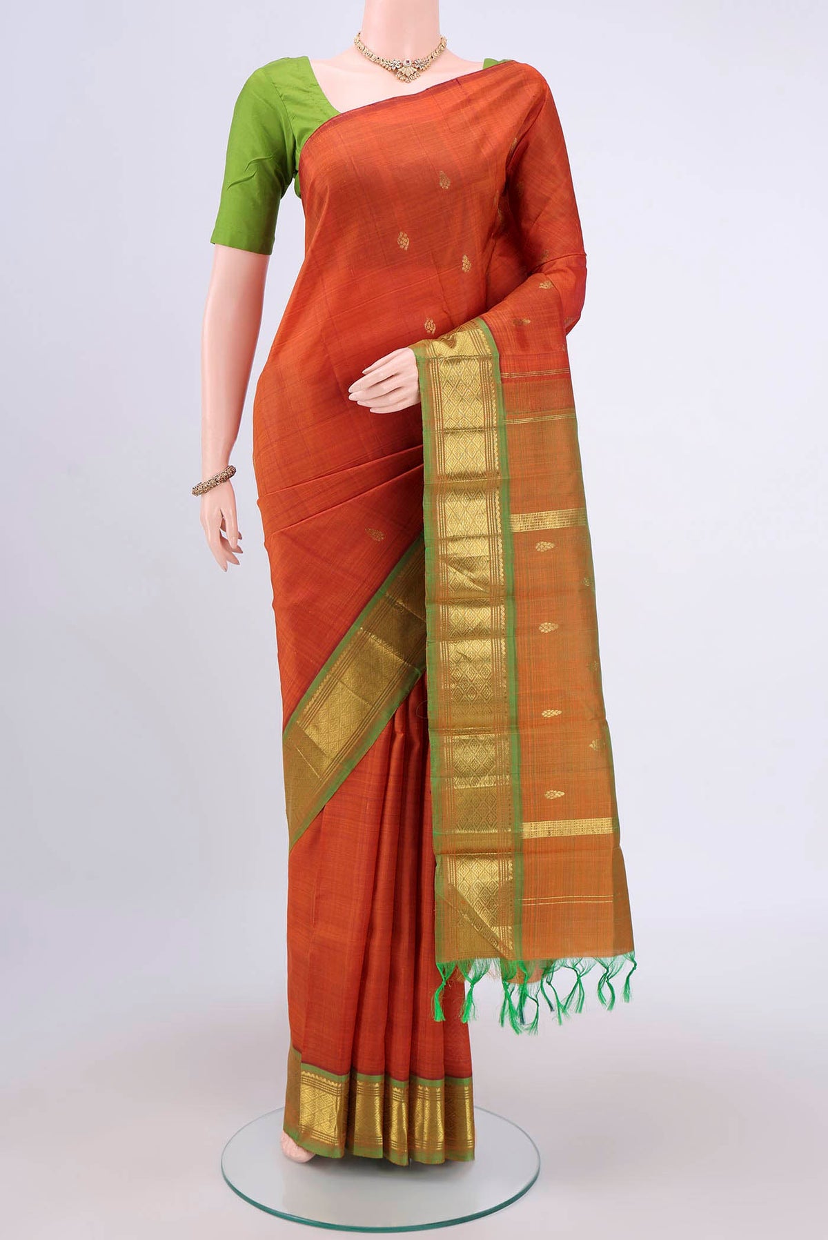 Rust Kanjivaram Silk Saree with Zari Butta on the body and One Side Border.  displayed on a mannequin