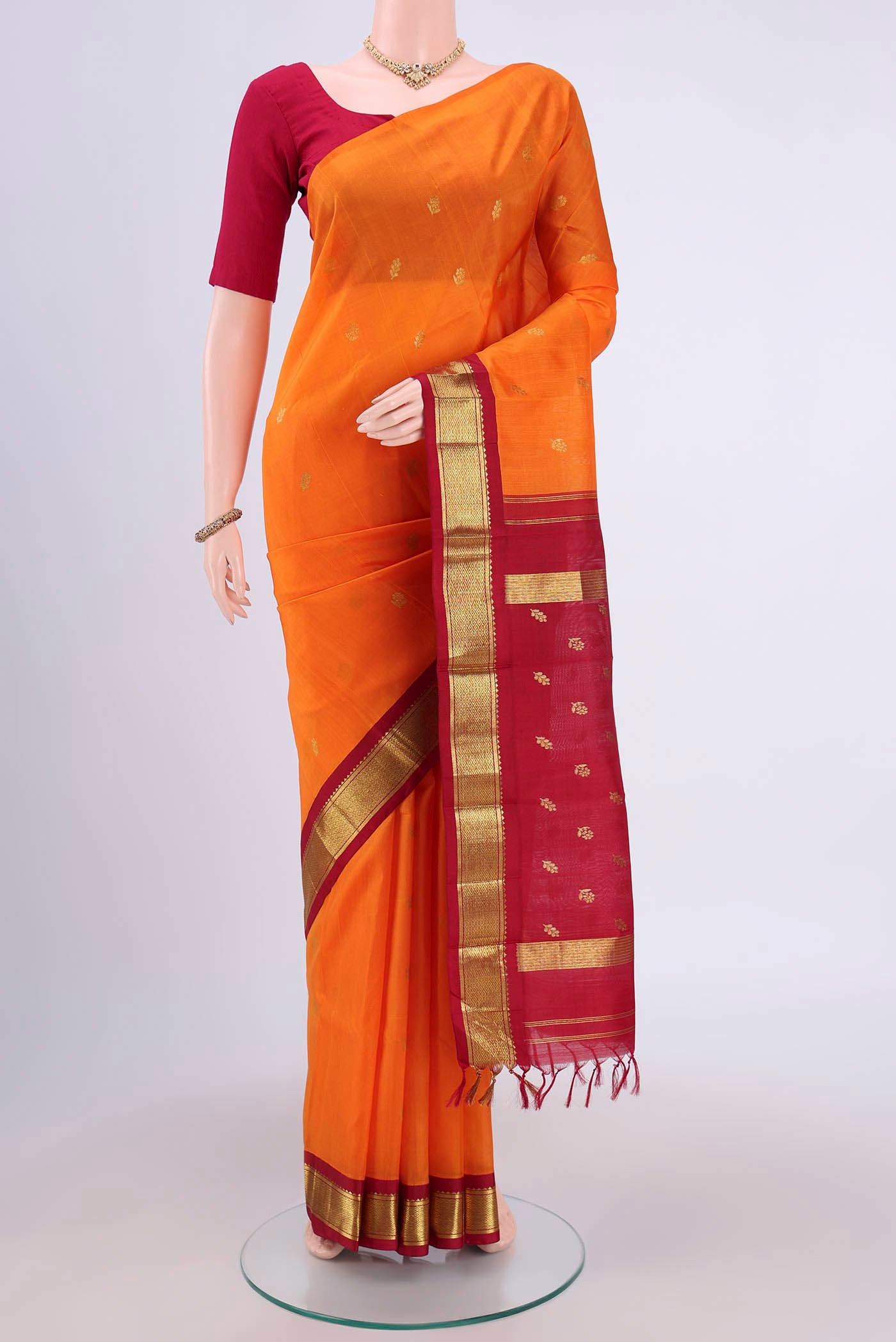 Orange Kanjivaram Silk Saree with Zari Butta on the body and One Side Border.  displayed on a mannequin