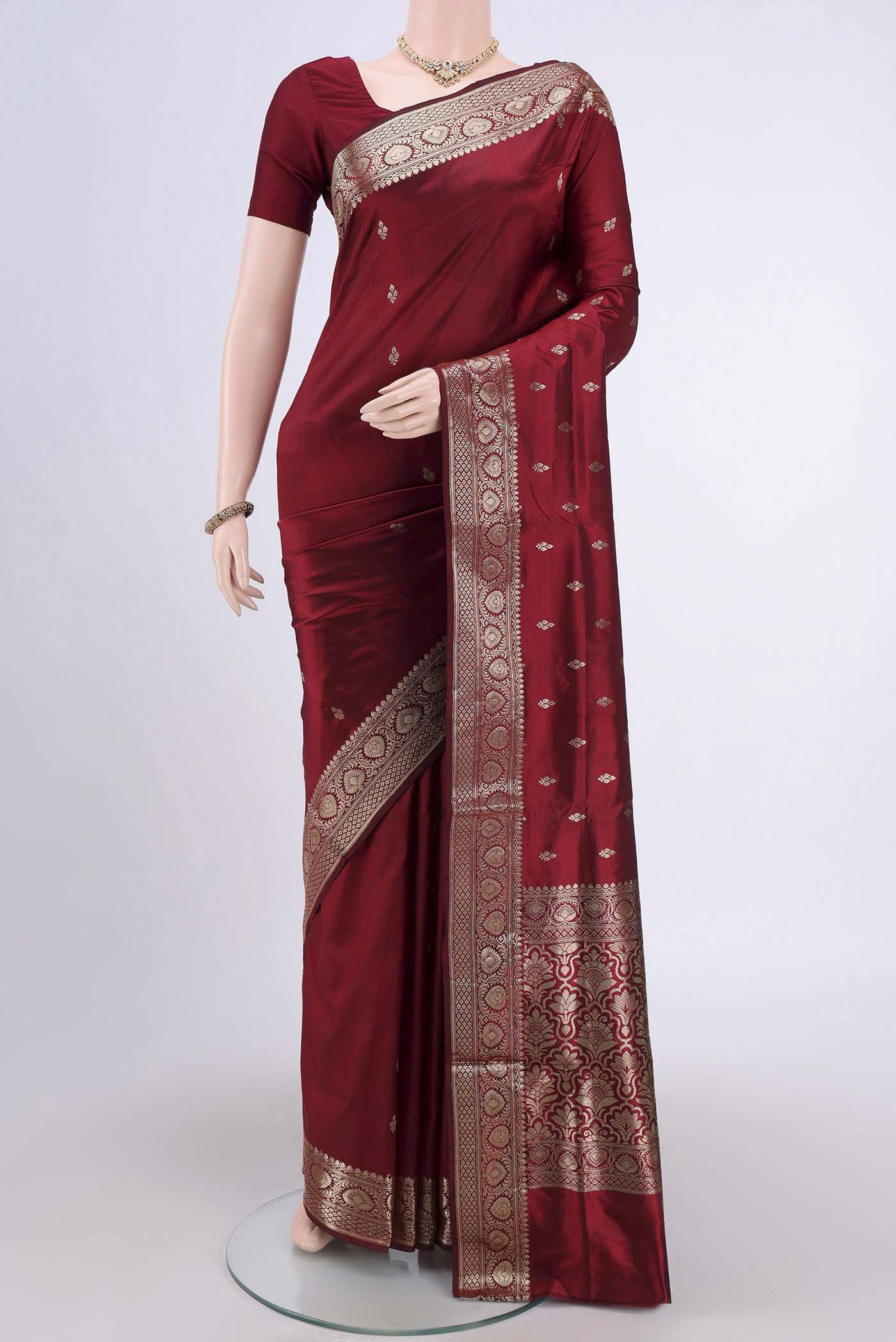 Maroon Banarasi Katan Silk Saree with Zari Butta on the body and Zari Border.  displayed on a mannequin