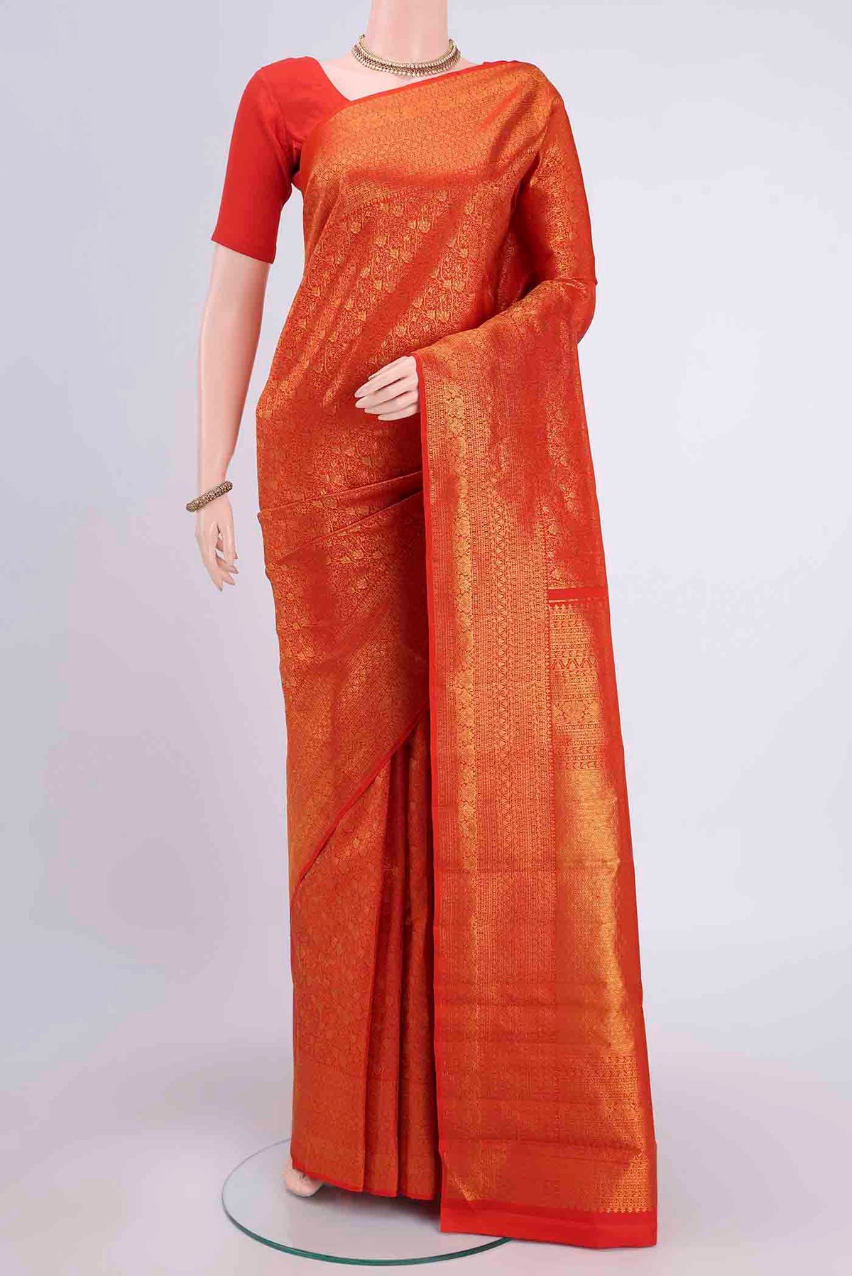 Orange Kanchipuram Silk Saree with Zari Brocade on the body and Zari Border displayed on a mannequin
