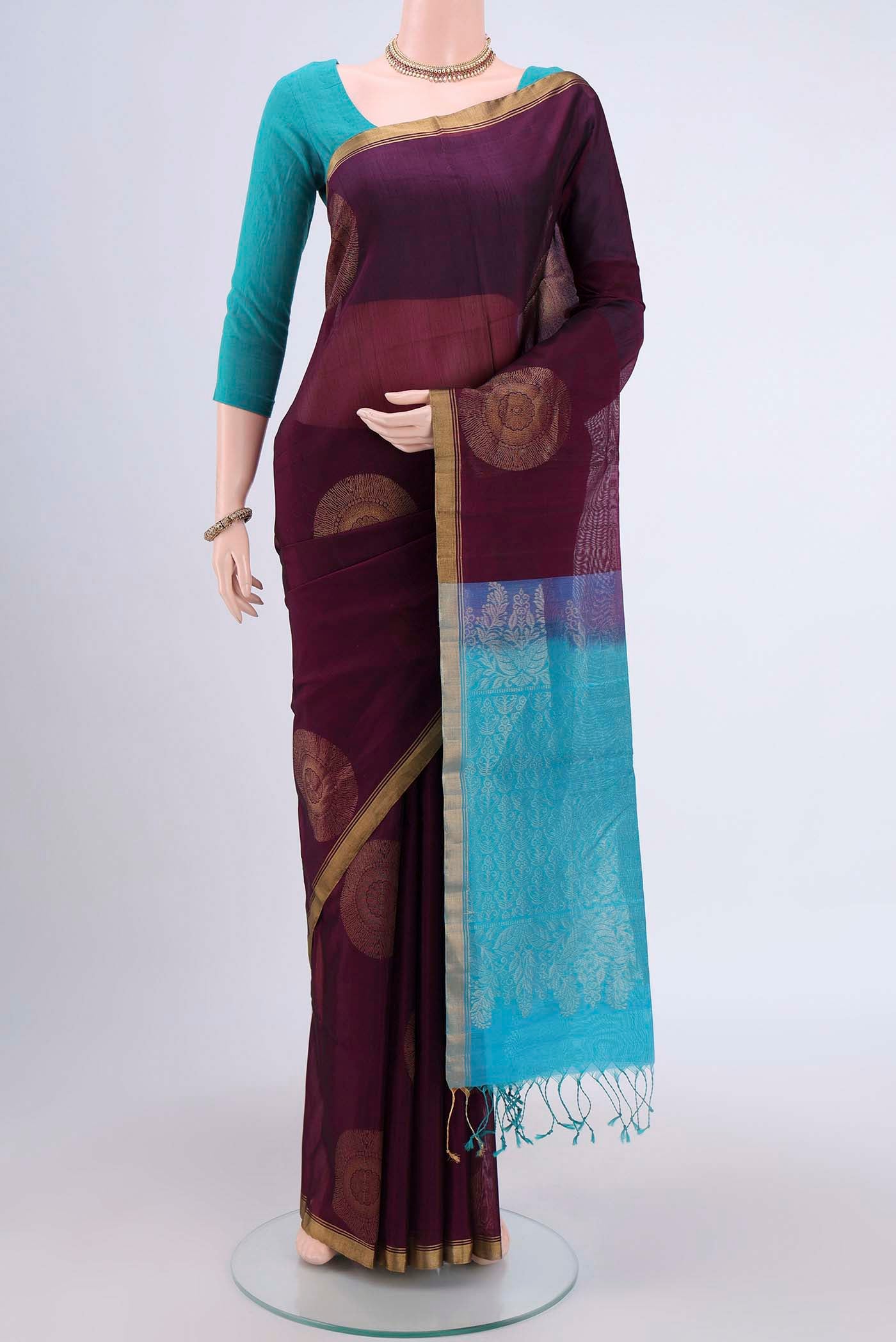 Burgundy Kora Cotton Saree with Zari Butta on the body and Zari Border.  displayed on a mannequin