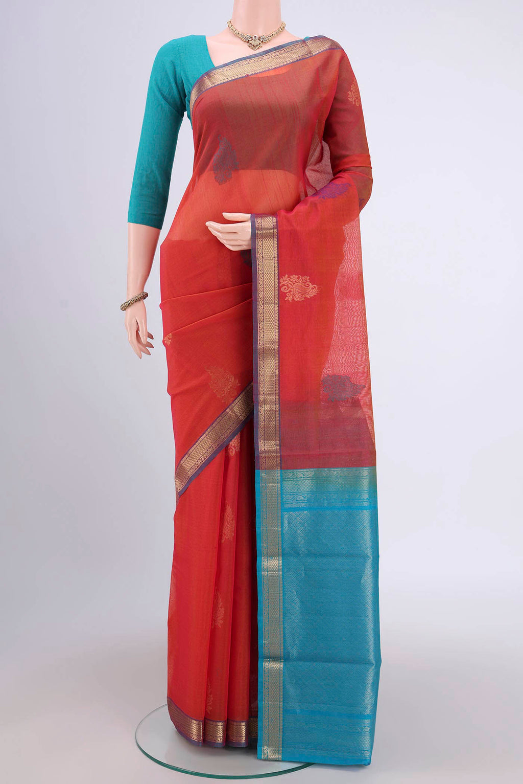 Rust Silk Cotton Saree with Zari Butta on the body and Zari Border.  displayed on a mannequin