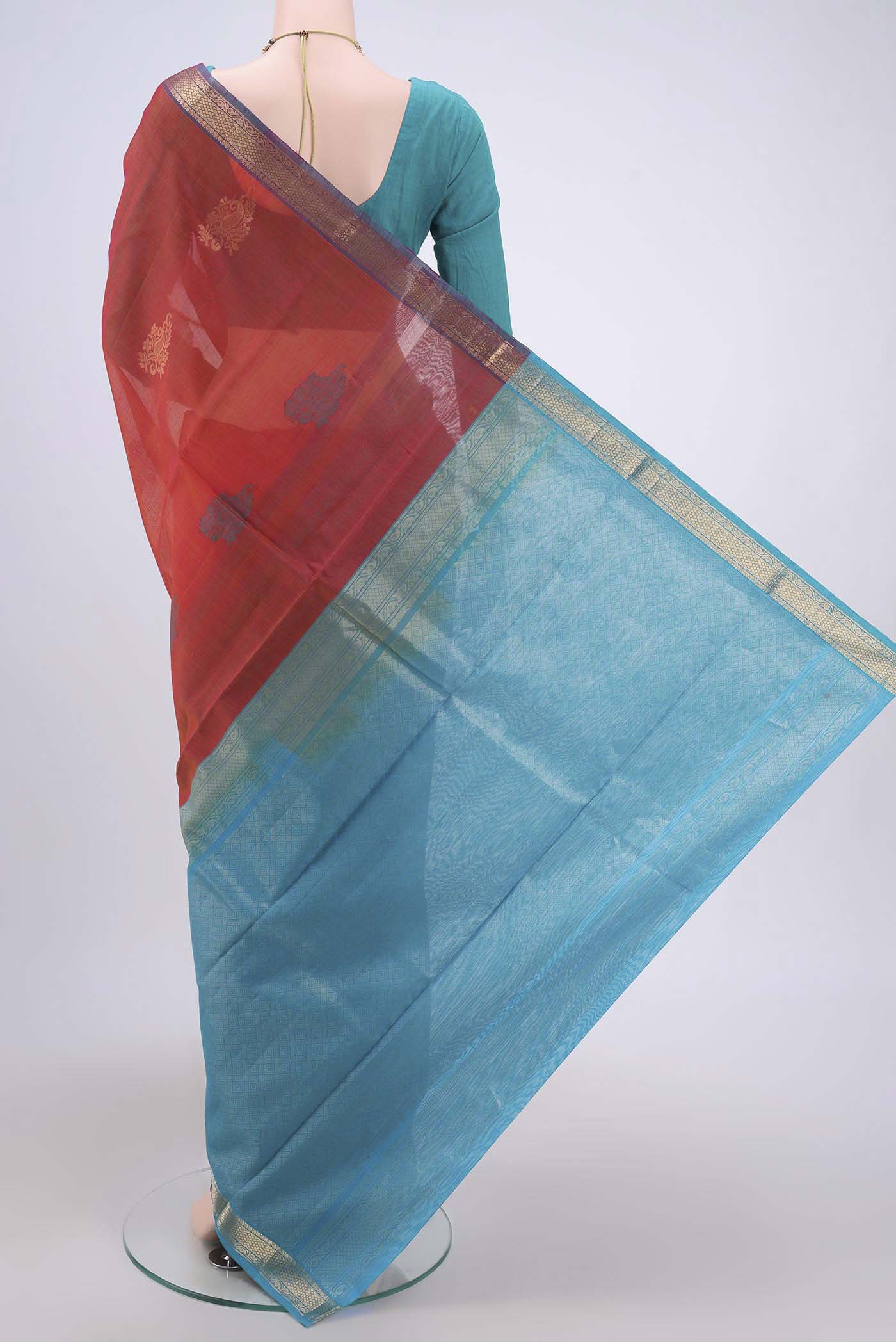 Flat view of Rust Silk Cotton Saree with Zari Butta on the body and Zari Border. 