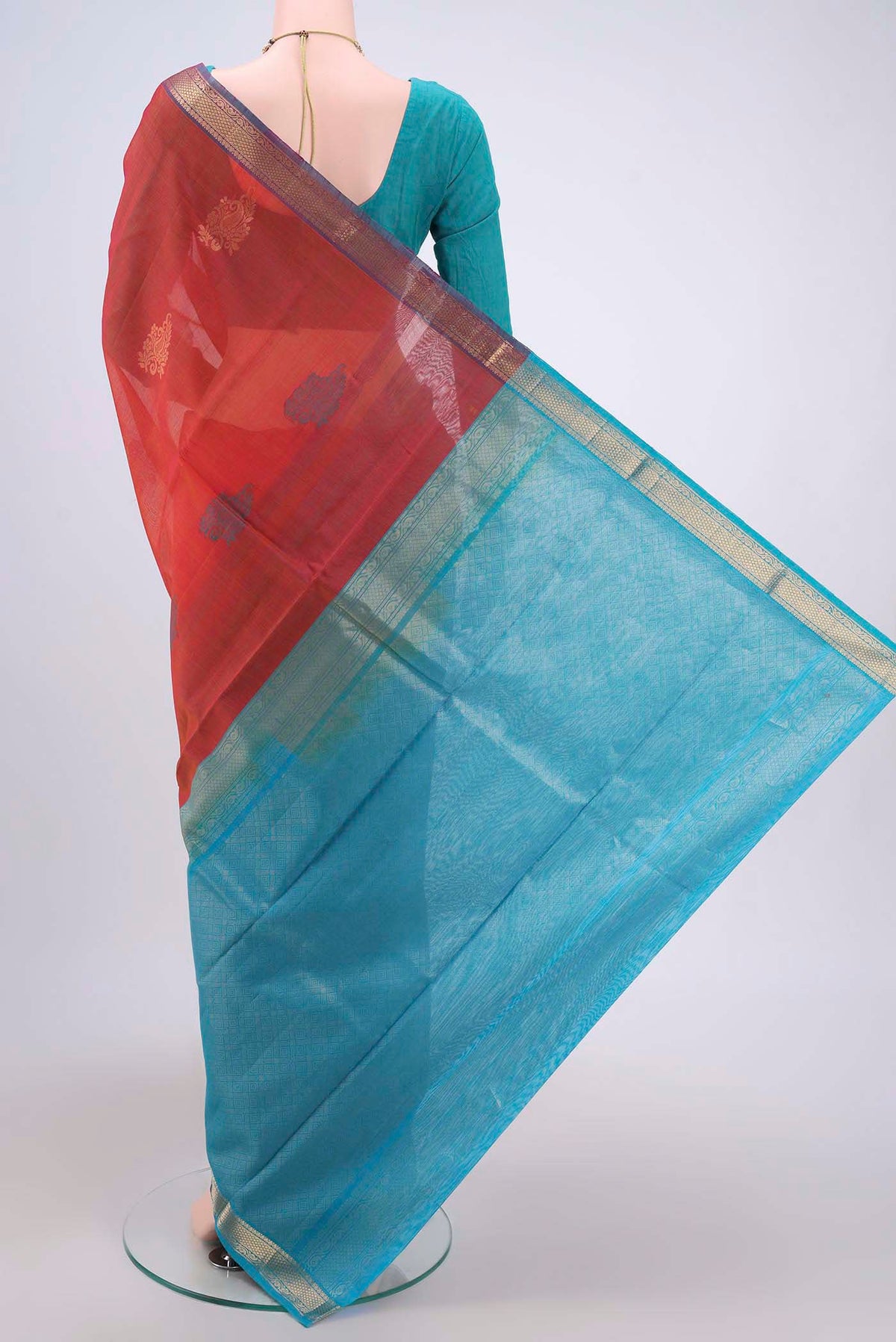 Flat view of Rust Silk Cotton Saree with Zari Butta on the body and Zari Border. 