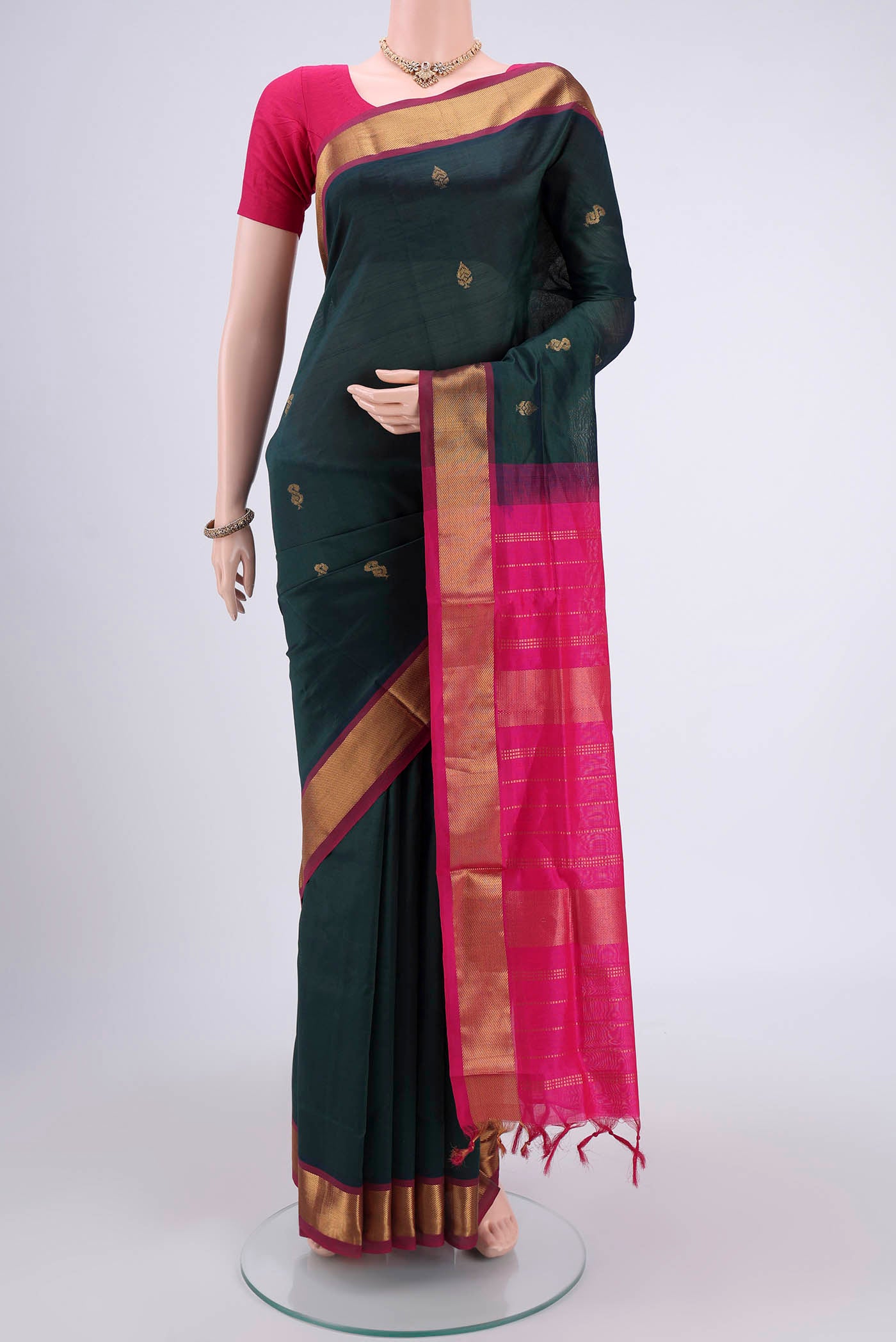 Bottle Green Blended Poly Cotton Saree with Zari Butta on the body and Thread Border.  displayed on a mannequin