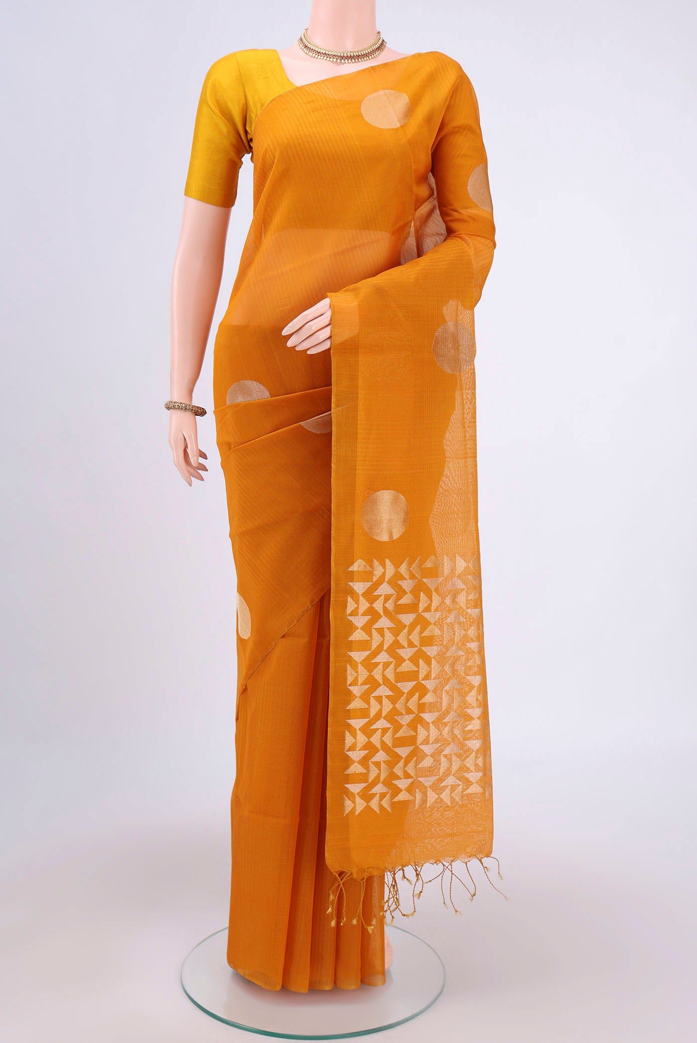 Mustard Kora Cotton Saree with Zari Butta on the body and Zari Border.  displayed on a mannequin