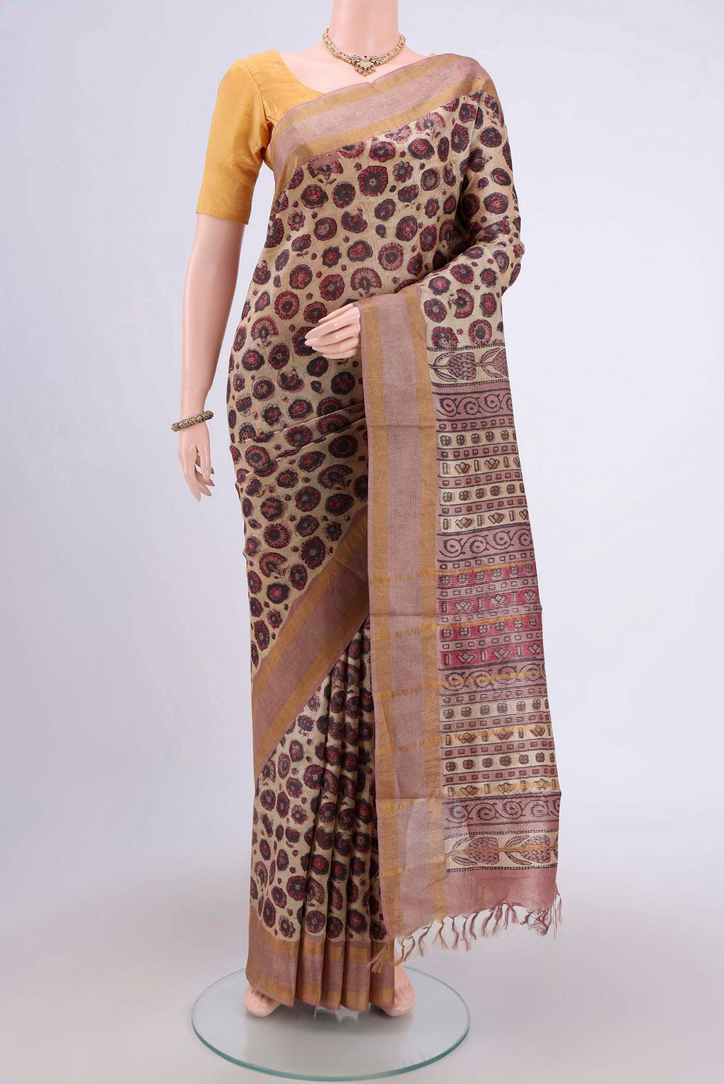 Beige Tussar Silk Saree with kalamkari Print on the body and Zari Border.  displayed on a mannequin