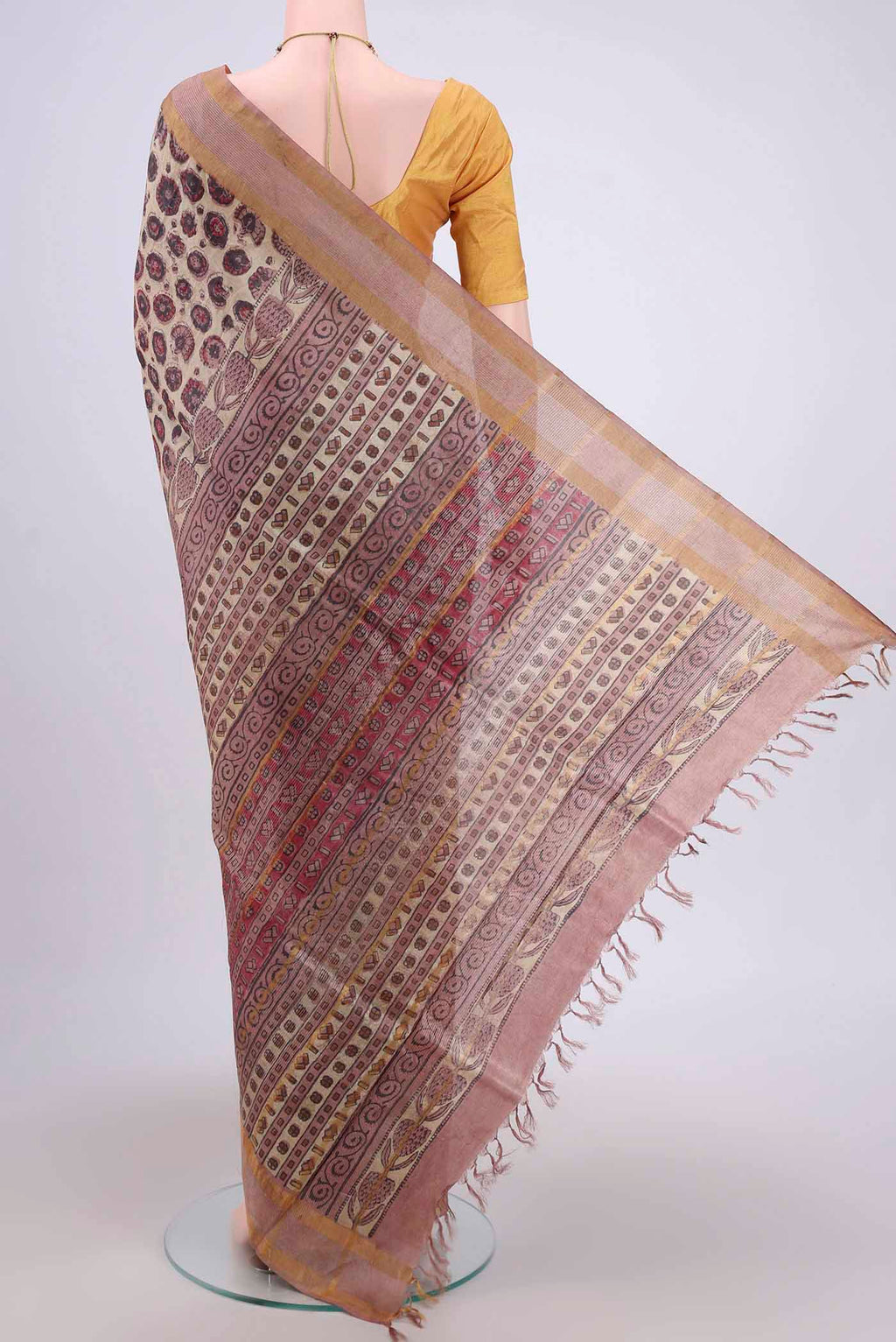 Flat view of Beige Tussar Silk Saree with kalamkari Print on the body and Zari Border. 