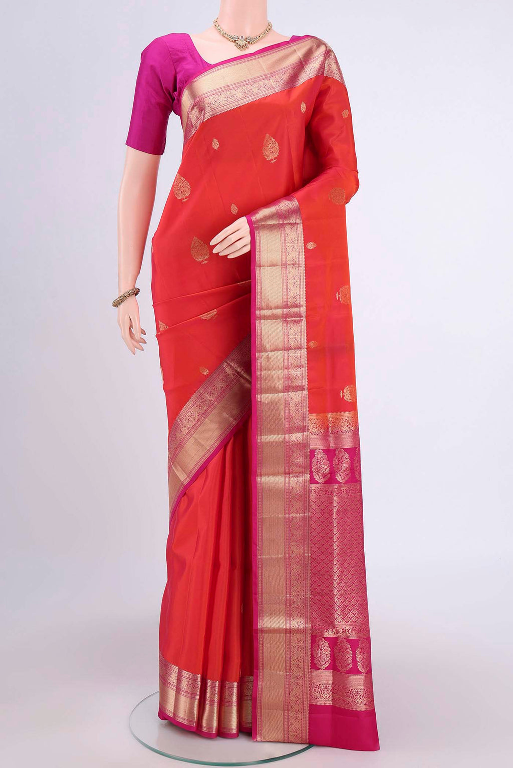 Brick Orange Soft Silk Saree with Zari Butta on the body and Zari Border.  displayed on a mannequin
