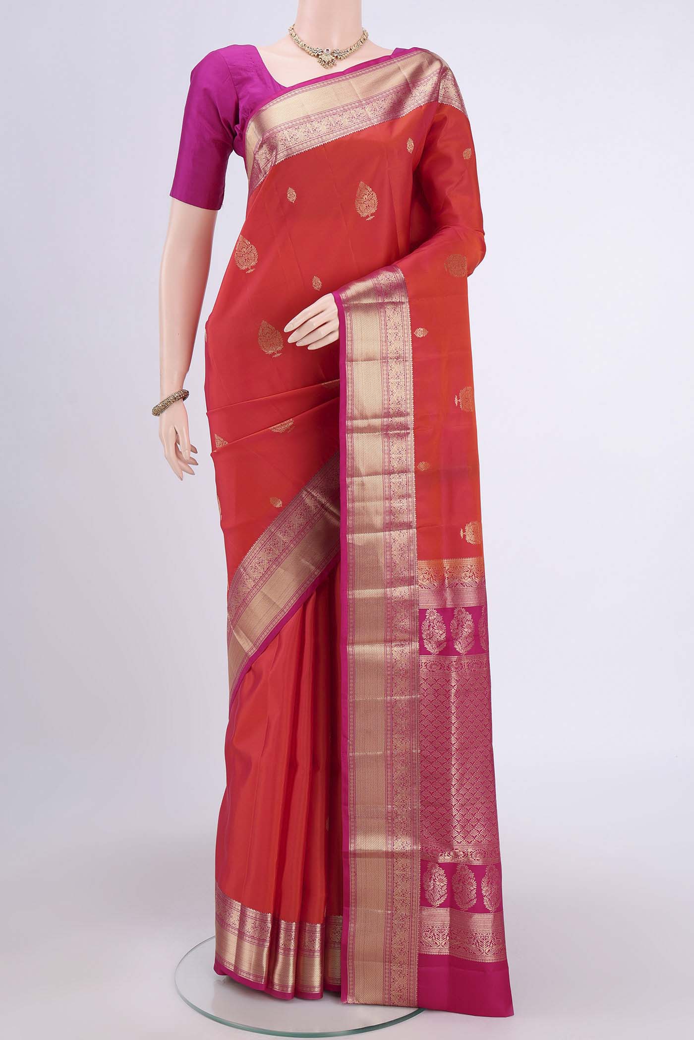 Brick Orange Soft Silk Saree with Zari Butta on the body and Zari Border.  displayed on a mannequin