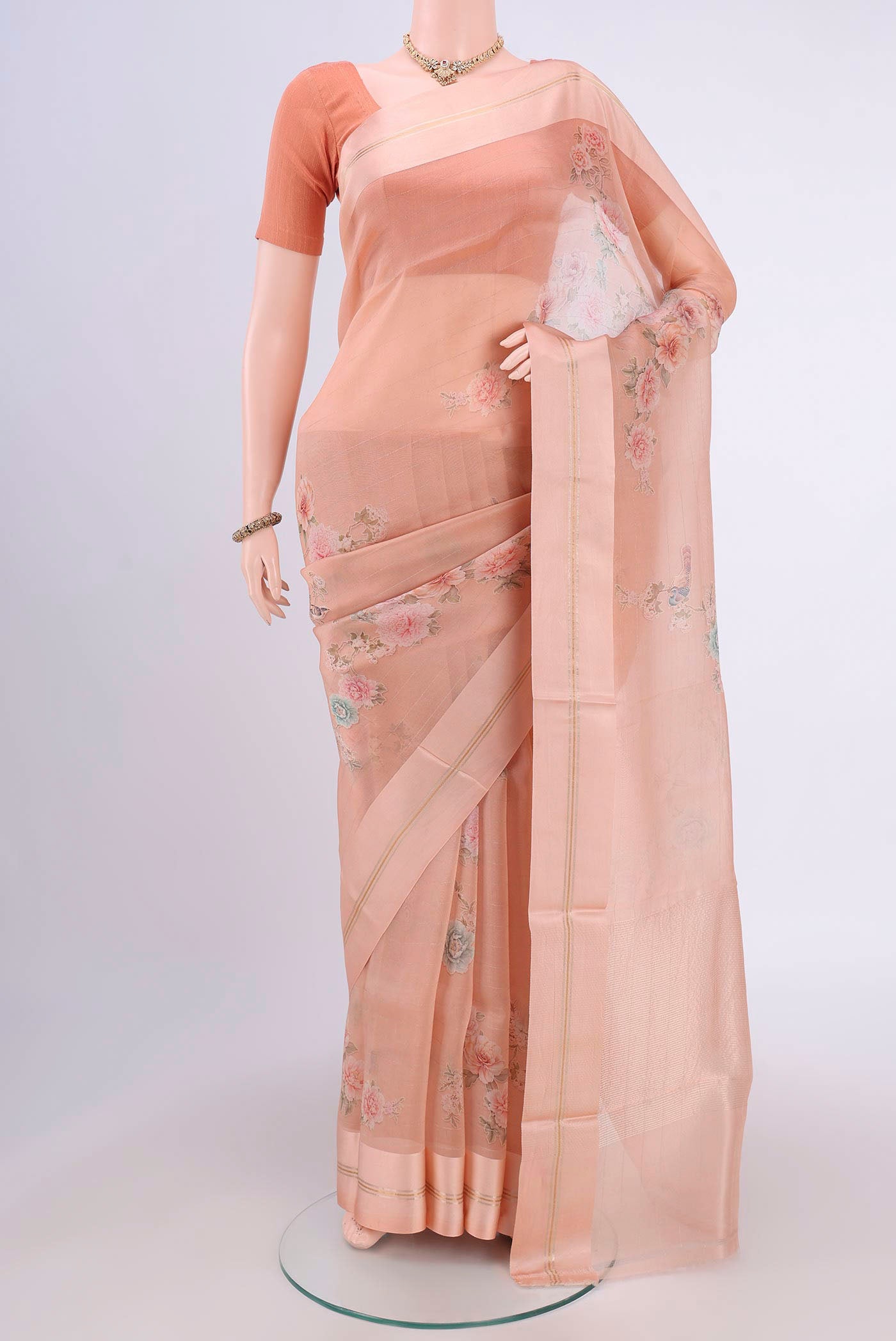 Peach Organza Silk Saree with Printed design on the body and Satin Border.  displayed on a mannequin