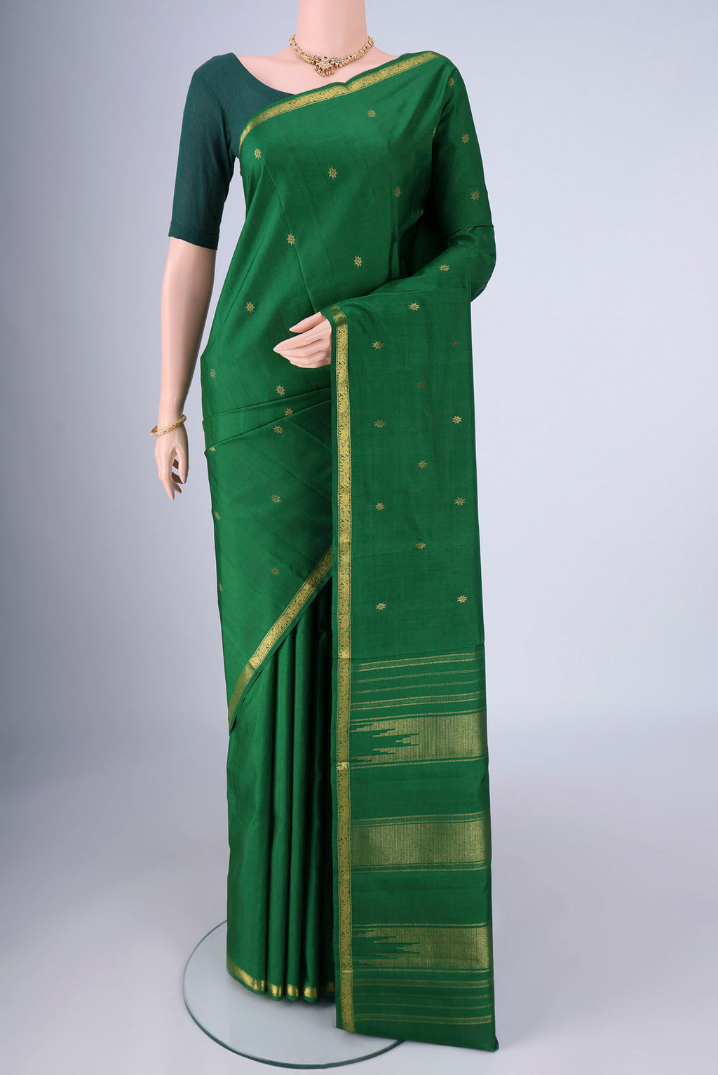 Green Kanchipuram Silk Saree with Zari Butta on the body and Zari Border.  displayed on a mannequin