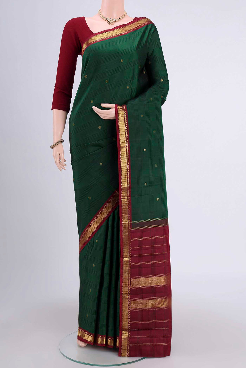 Bottle Green Kanchipuram Saree with Zari Butta on the body and Zari Border.  displayed on a mannequin