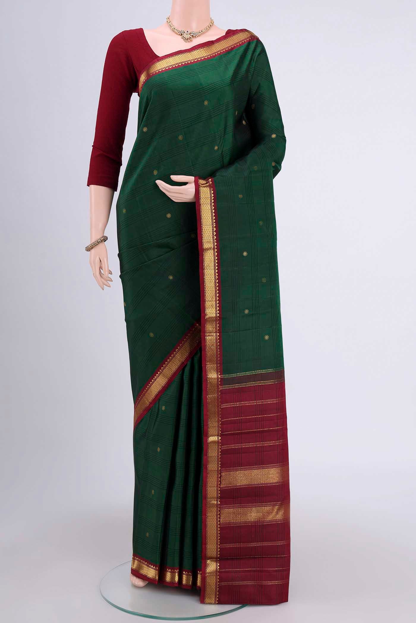 Bottle Green Kanchipuram Saree with Zari Butta on the body and Zari Border.  displayed on a mannequin