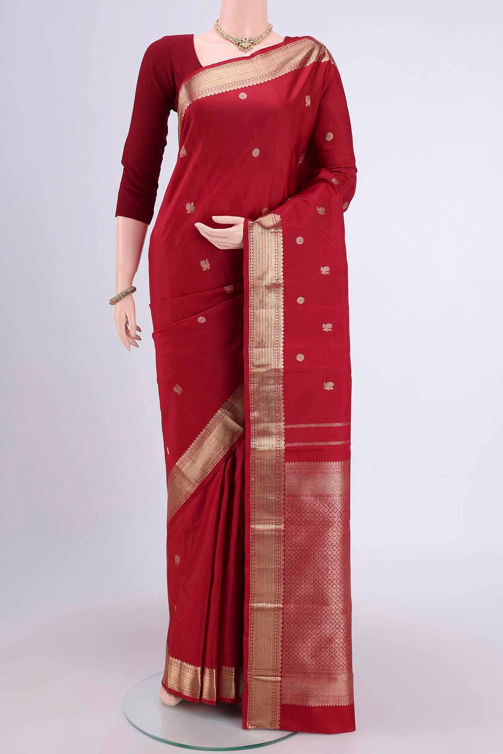 Maroon Kanjivaram Saree with Zari Butta on the body and Zari Border.  displayed on a mannequin