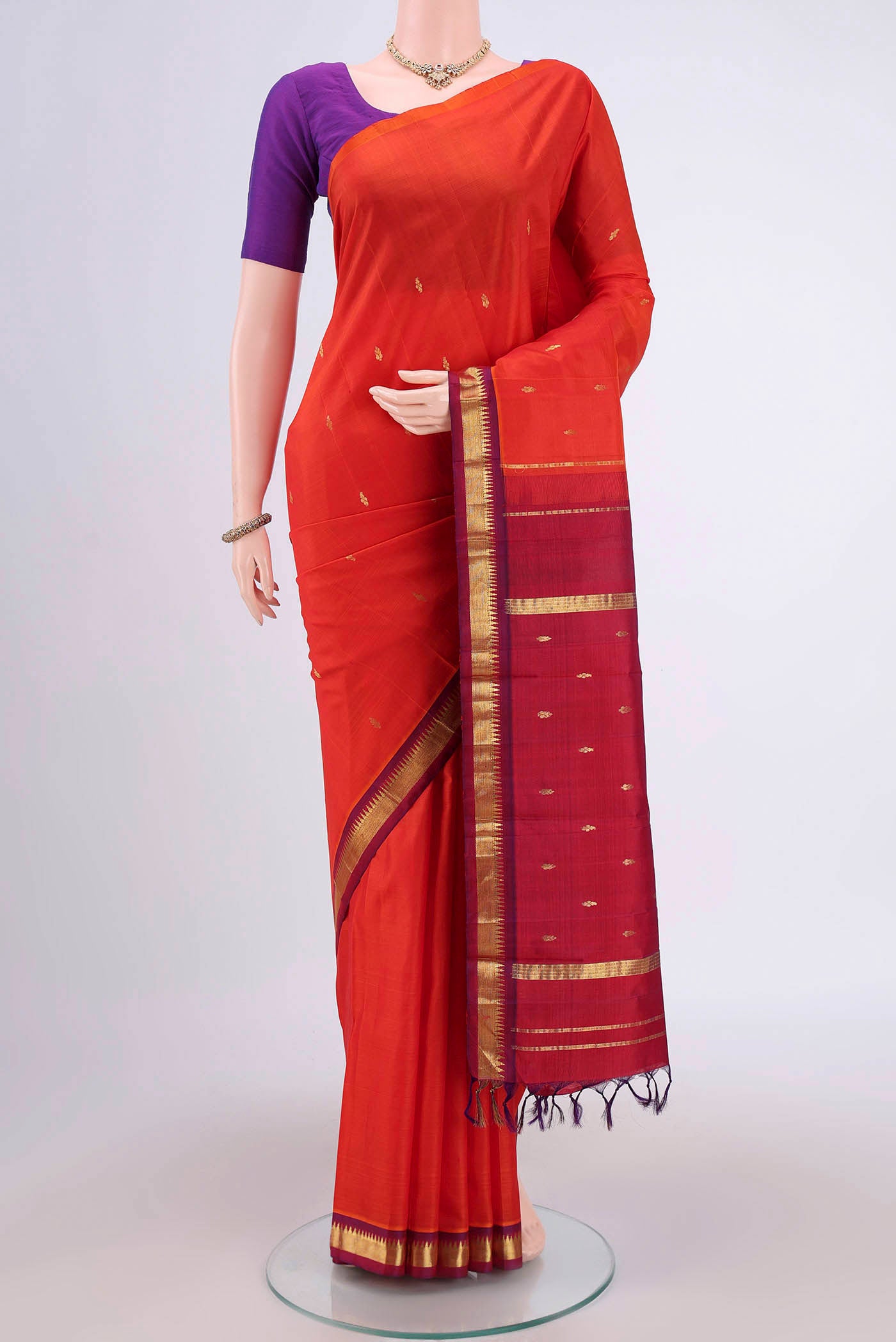 Orange Kanjivaram Silk Saree with Zari Butta on the body and One Side Border.  displayed on a mannequin