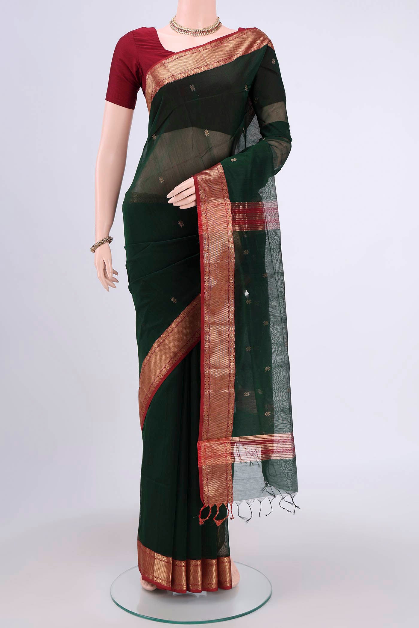 Bottle Green Maheshwari Silk Cotton Saree with Zari Butta on the body and Zari Border.  displayed on a mannequin