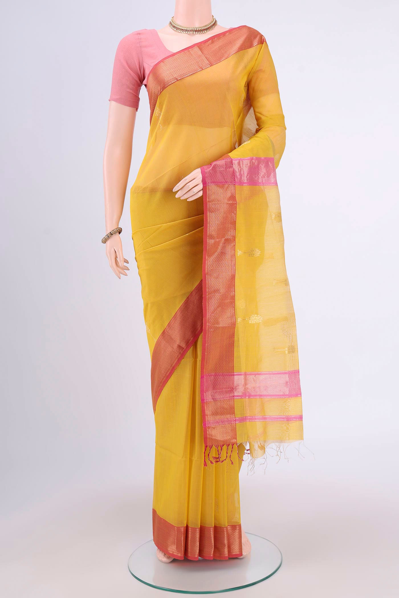 Mustard Maheshwari Silk Cotton Saree with Zari Butta on the body and Zari Border.  displayed on a mannequin