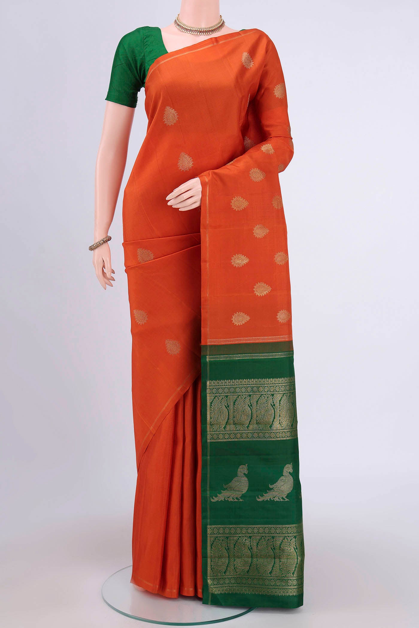 Pure Silk Pure Zari Rust Kanchipuram Saree with Zari Butta on the body and Thin Zari Line.  displayed on a mannequin