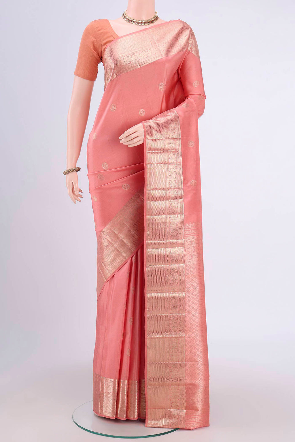 Peach Kanjivaram Saree with Zari Butta on the body and Zari Border.  displayed on a mannequin