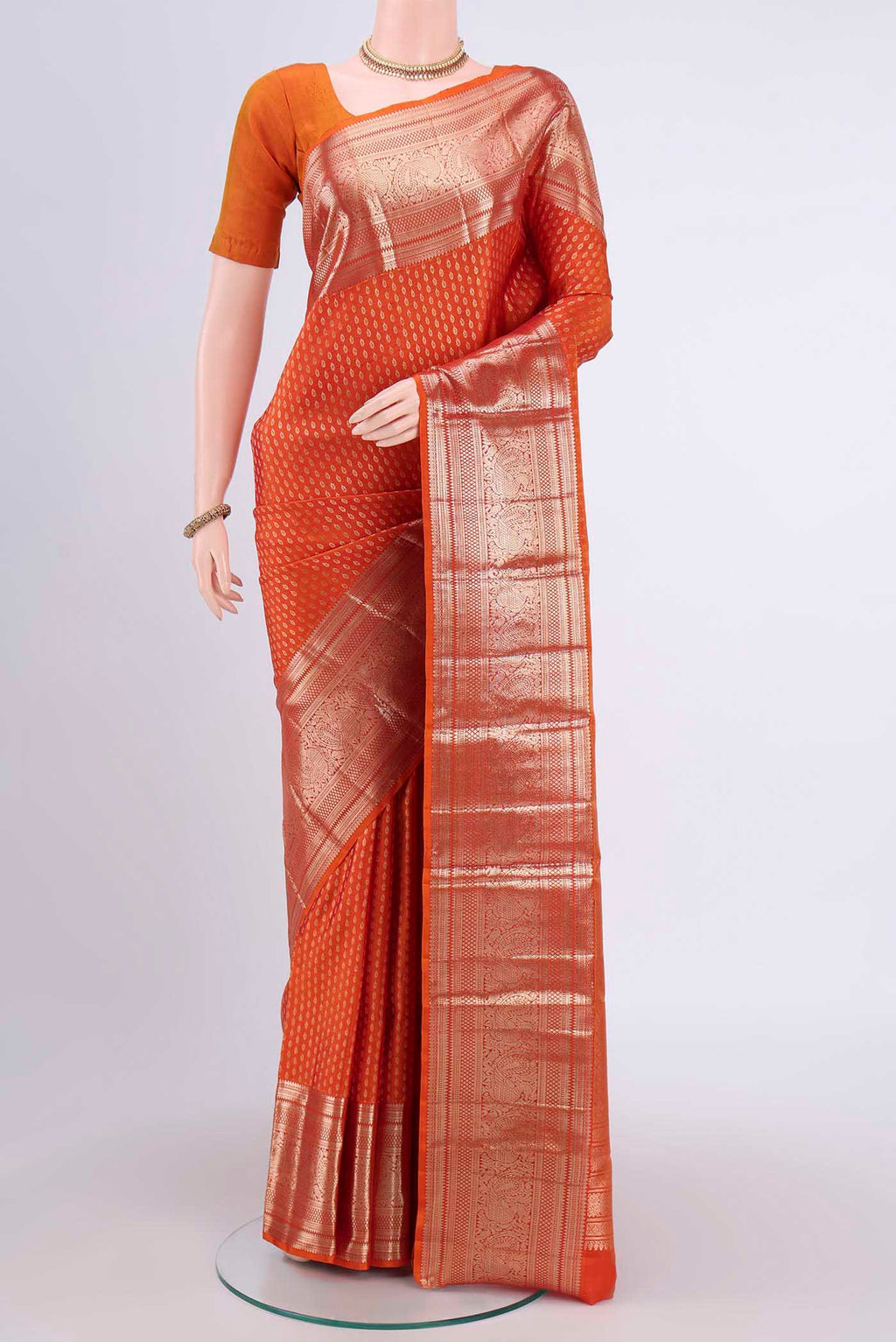 Rust Kanchipuram Saree with Zari Butta on the body and Zari Border.  displayed on a mannequin