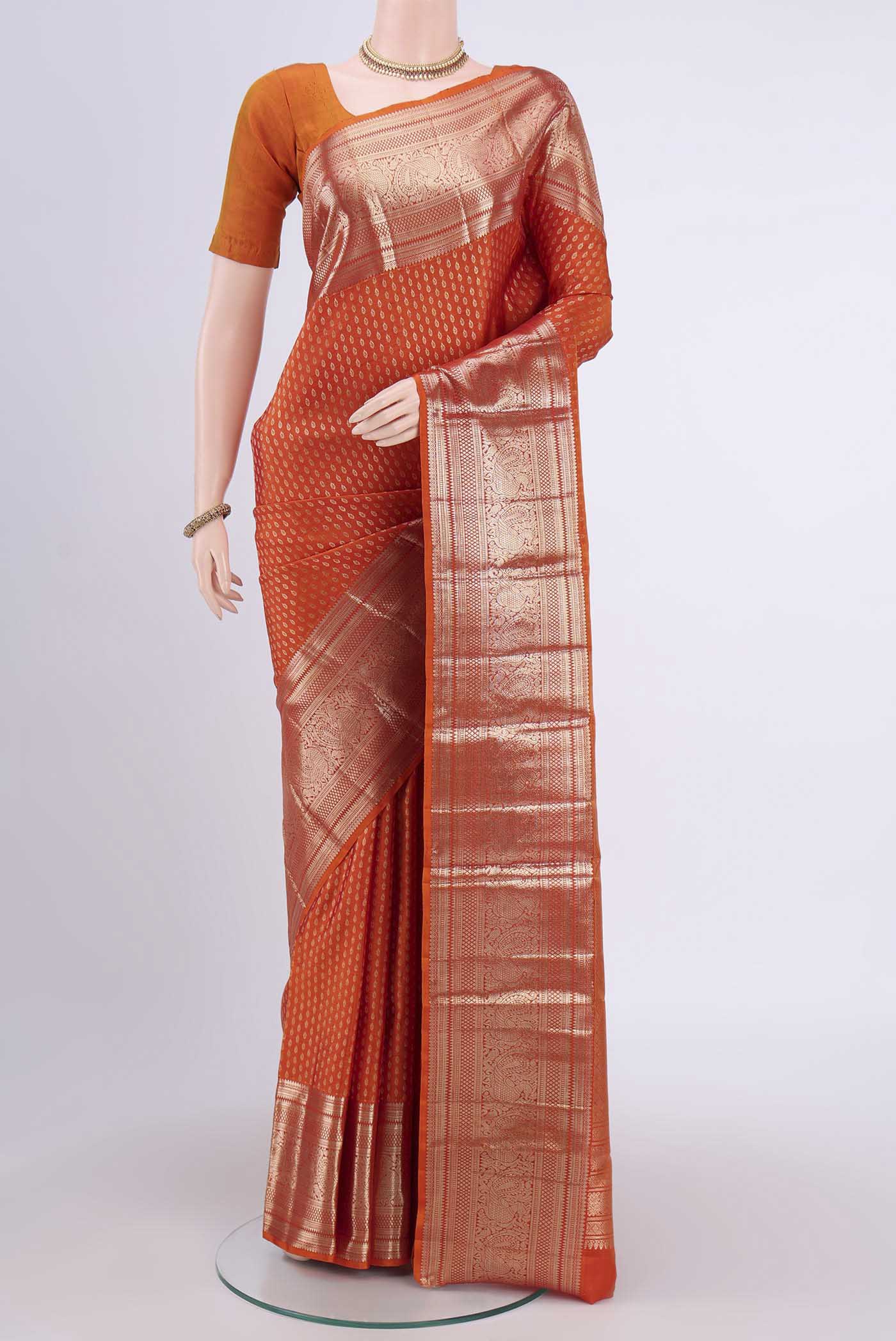 Rust Kanchipuram Saree with Zari Butta on the body and Zari Border.  displayed on a mannequin