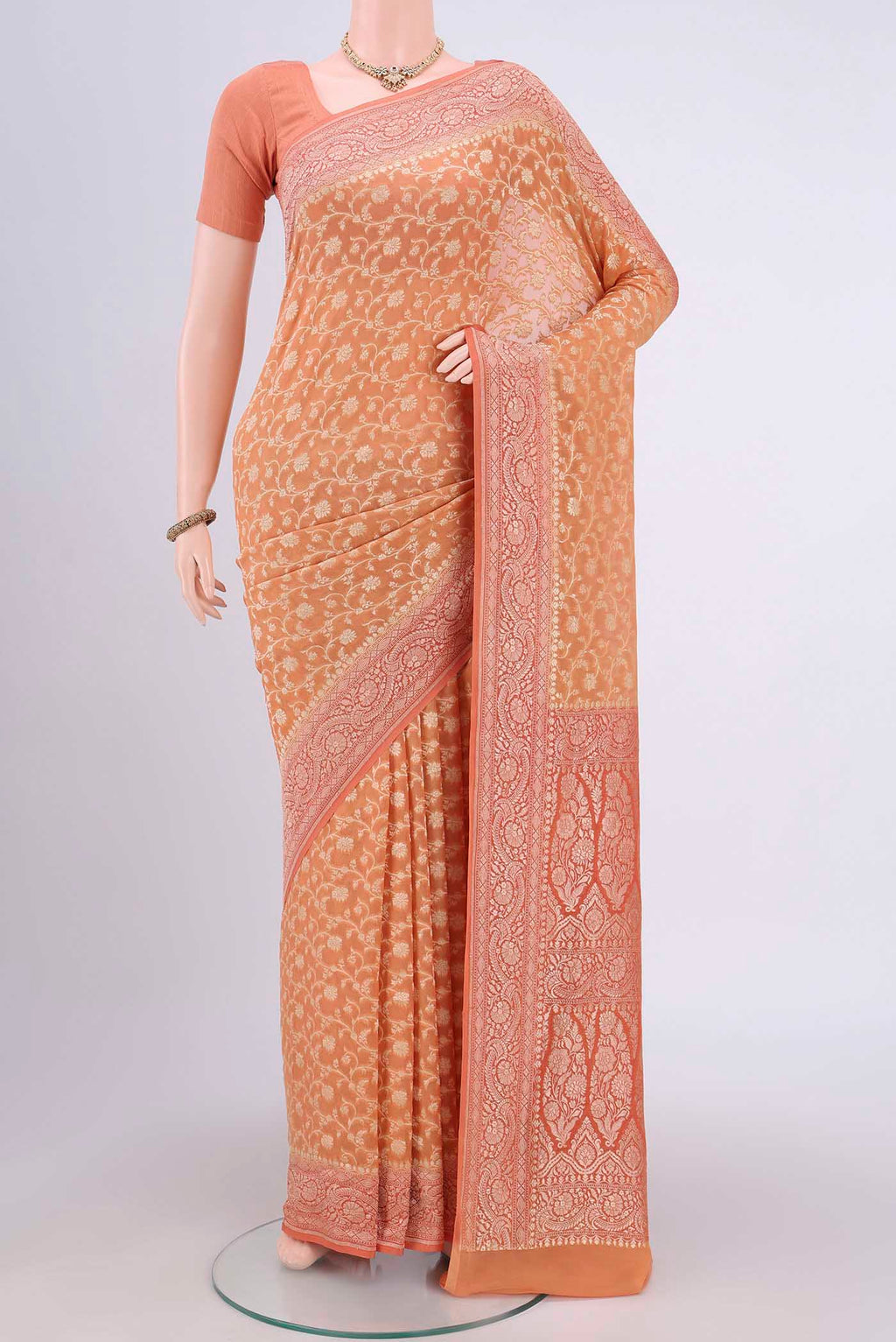 Peach Banarasi Georgette Saree with Zari Brocade on the body and Zari Border.  displayed on a mannequin